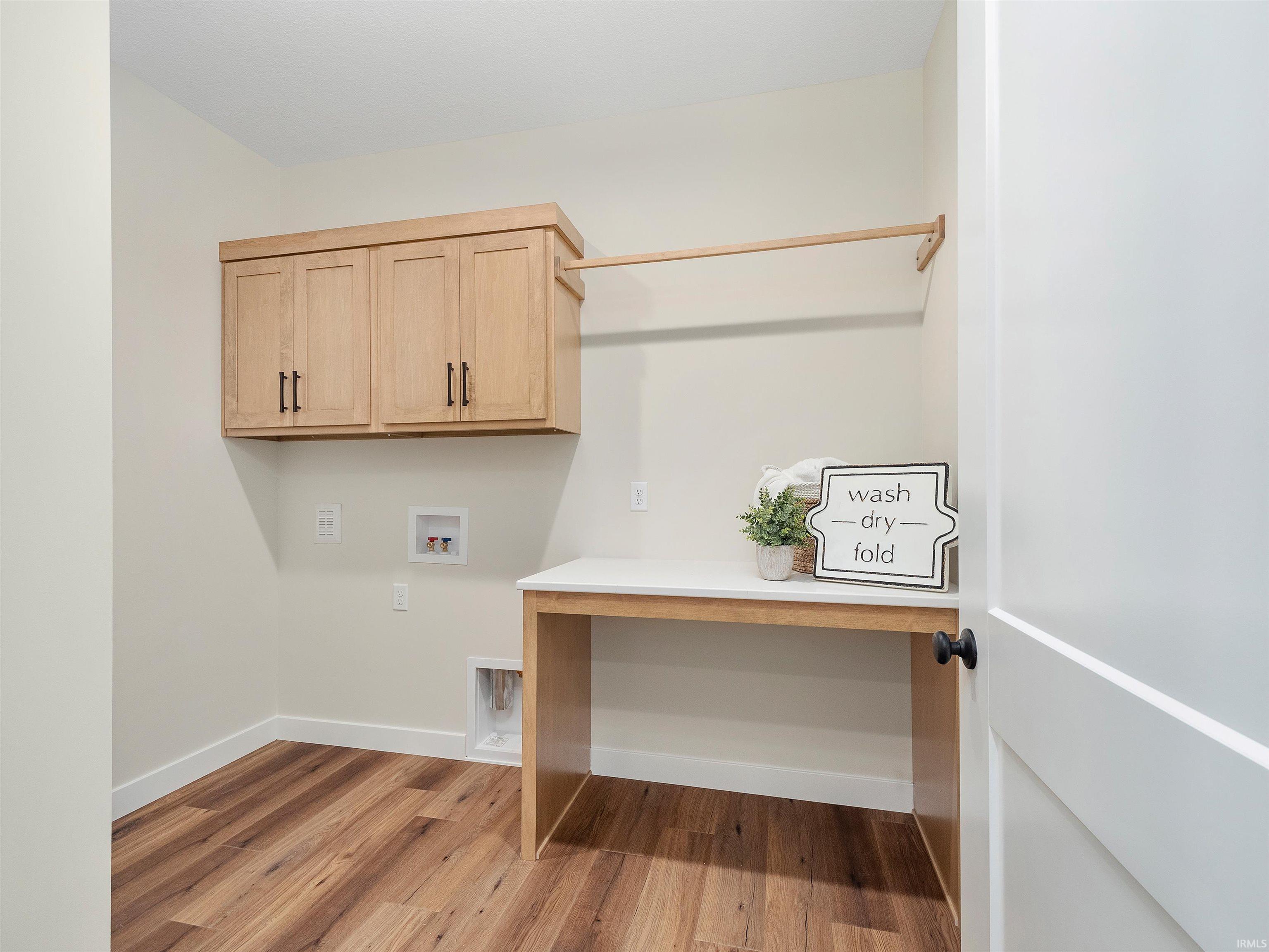Laundry Room with LVP flooring, hookup for a washer and dryer, and custom cabinets