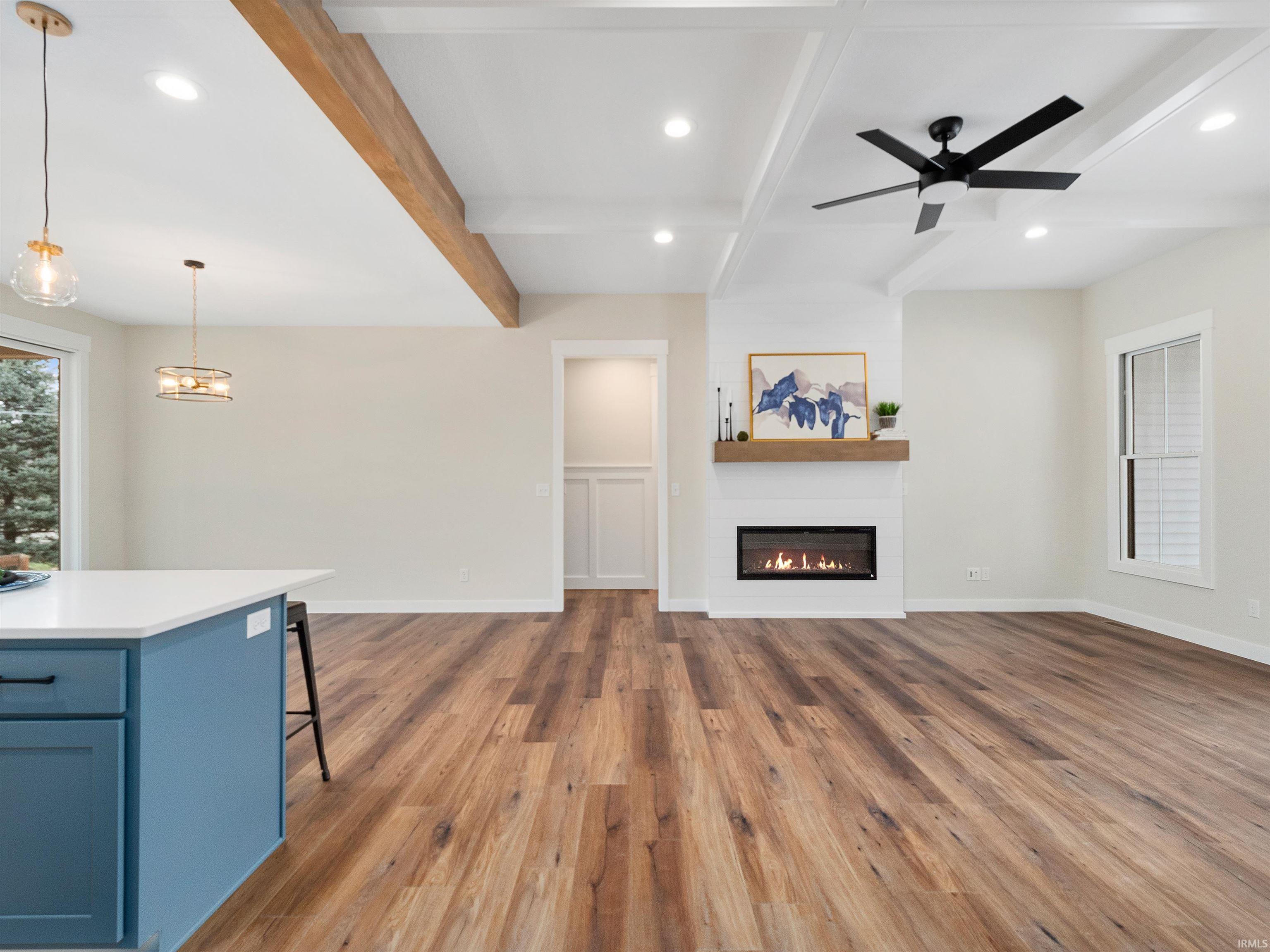 New Build living room with coffered ceiling, beamed ceiling, wideplank LVP flooring, recessed lighting, and a fireplace