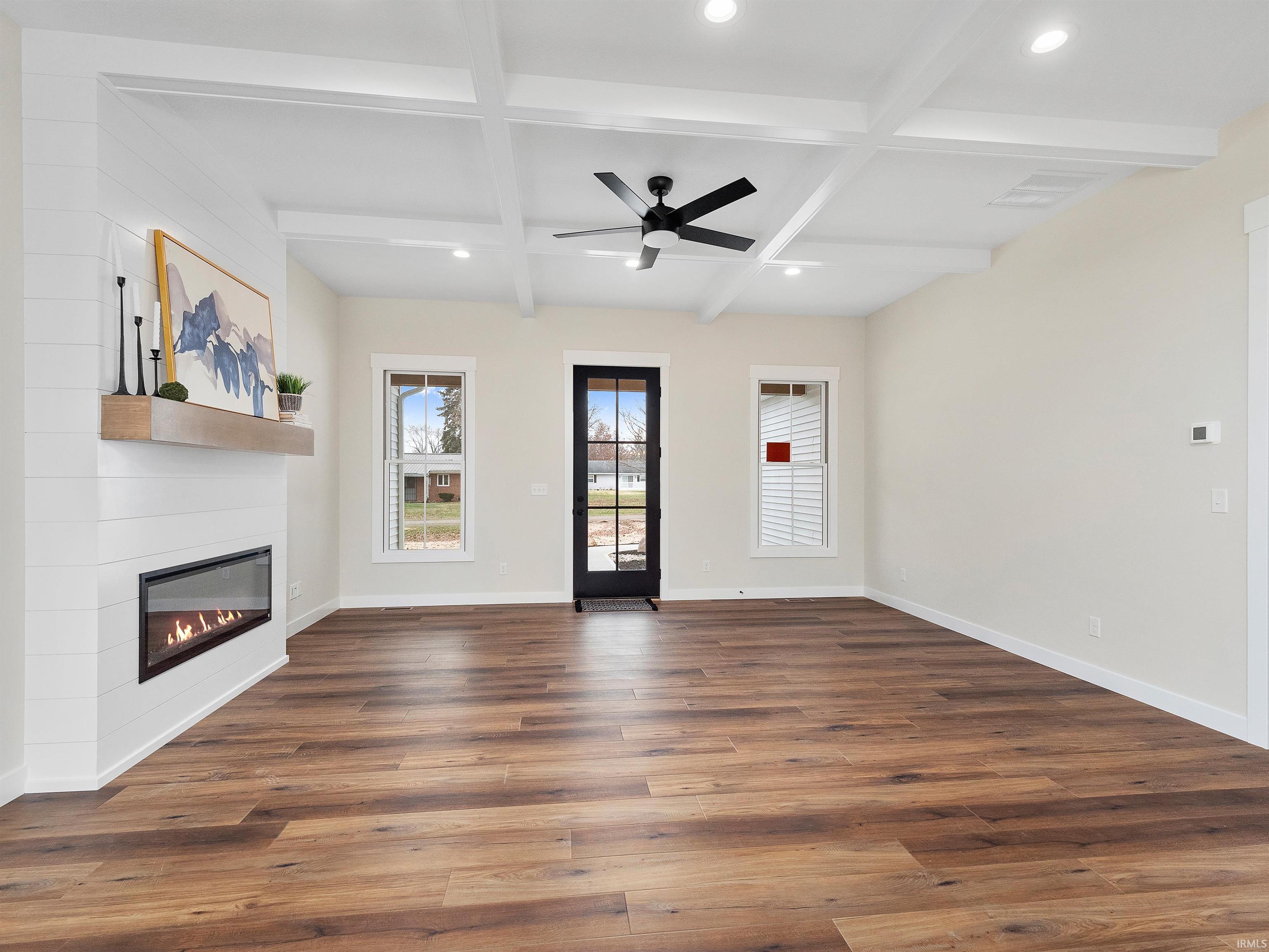 New Build living room with coffered ceiling, beamed ceiling, wideplank LVP flooring, recessed lighting, and a fireplace