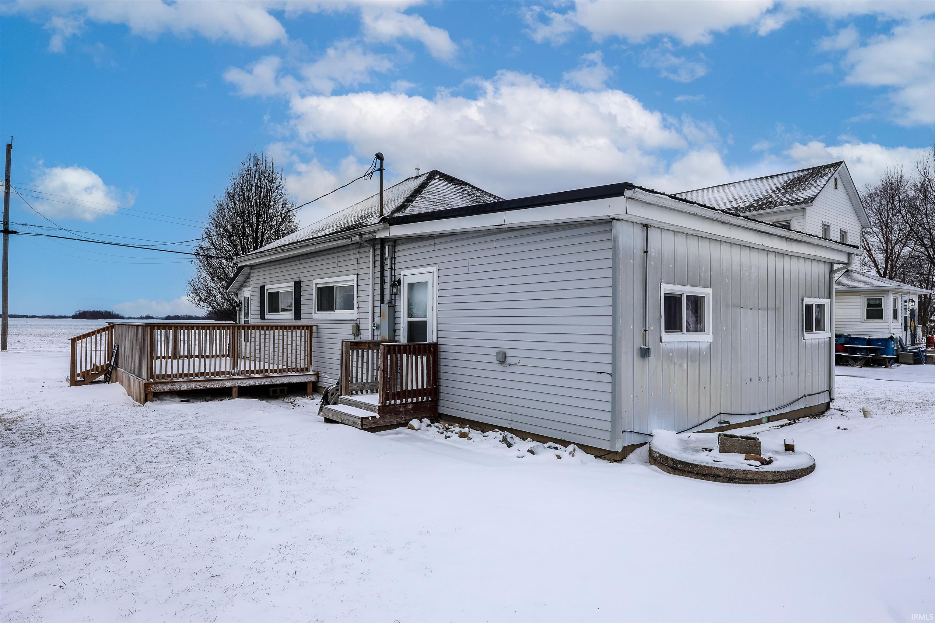 Snow covered back of property with a wooden deck