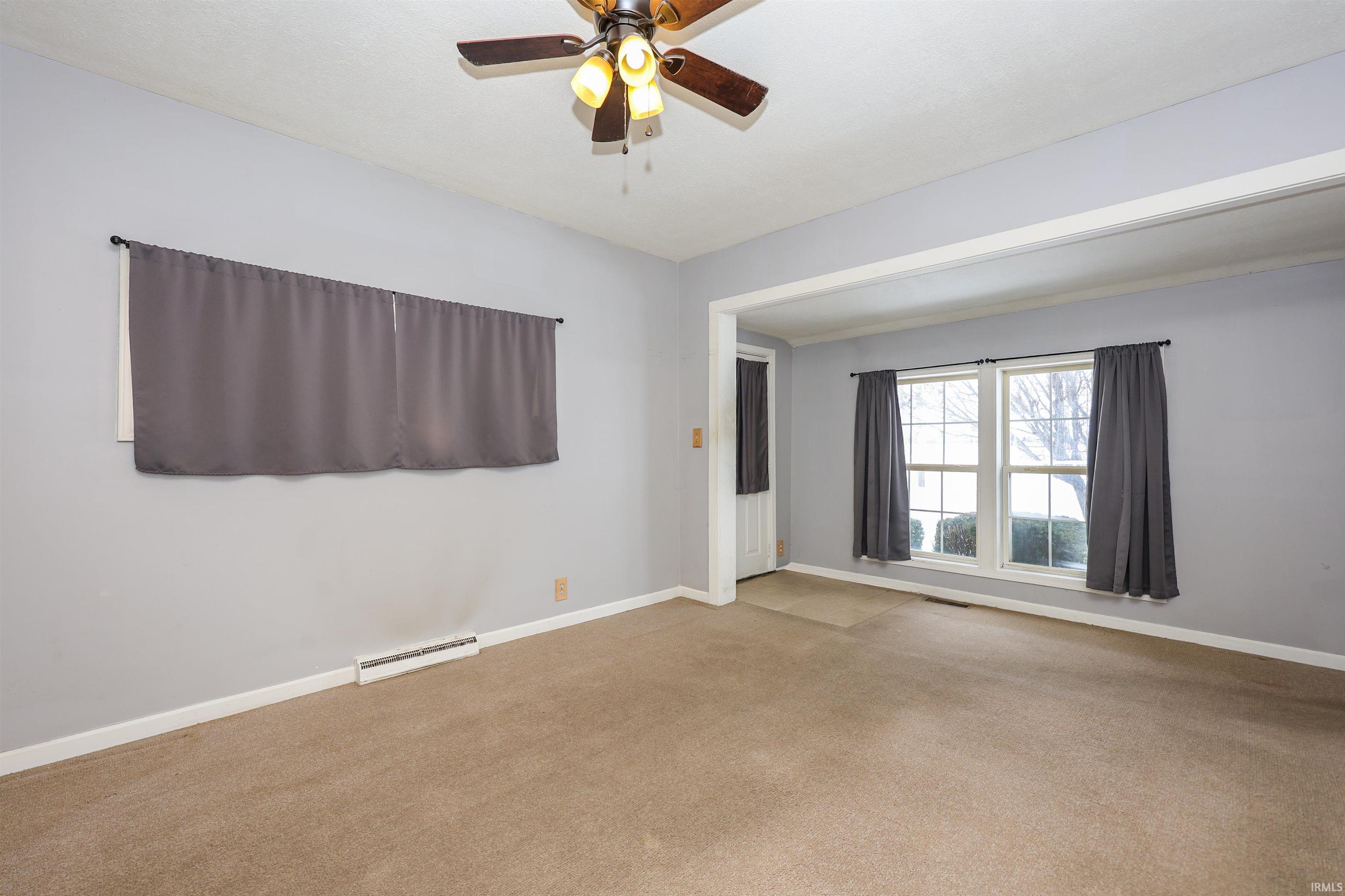 Empty room featuring ceiling fan, carpet flooring, and baseboard heating