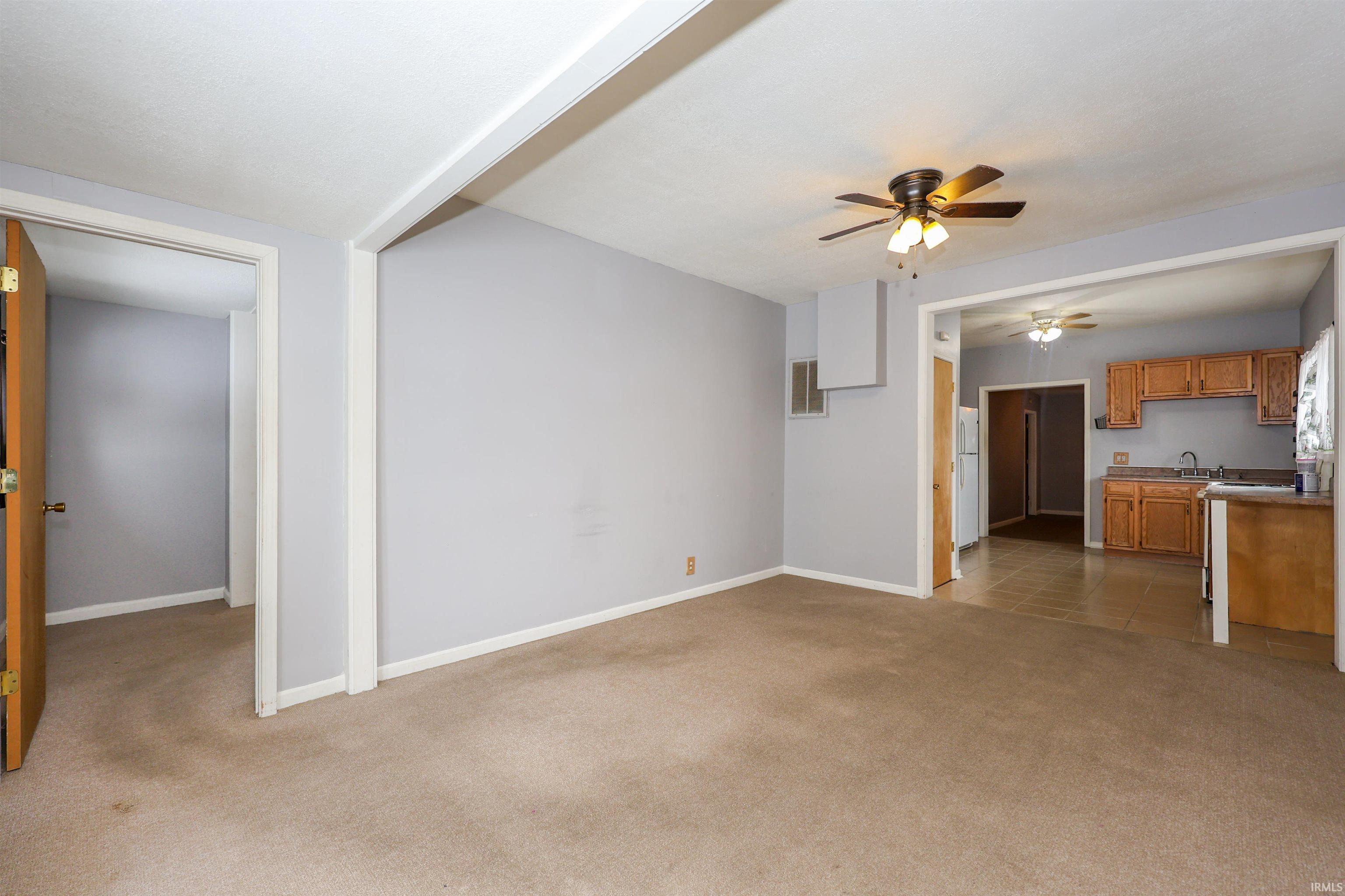 Unfurnished living room with light colored carpet and a ceiling fan