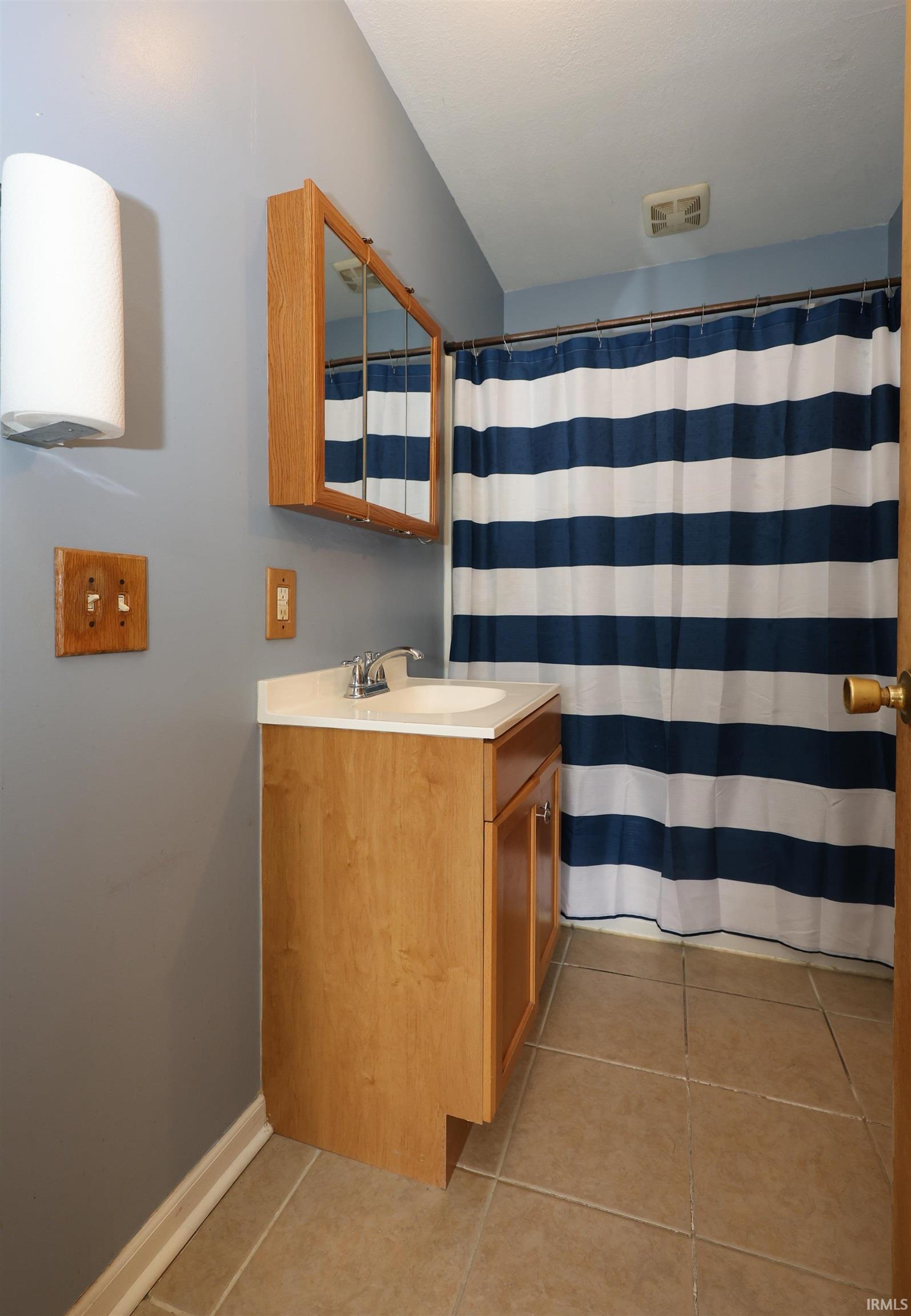 Bathroom featuring a shower with curtain, vanity, and light tile patterned floors