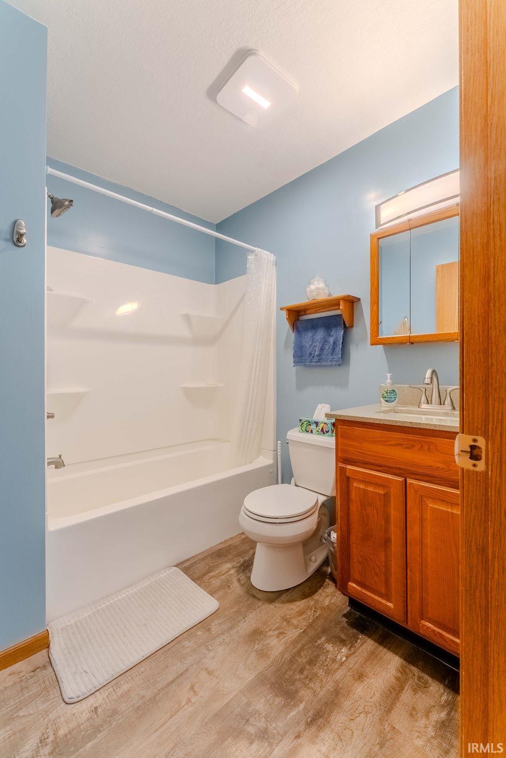 Bathroom featuring light wood-type flooring, vanity, and shower / tub combo