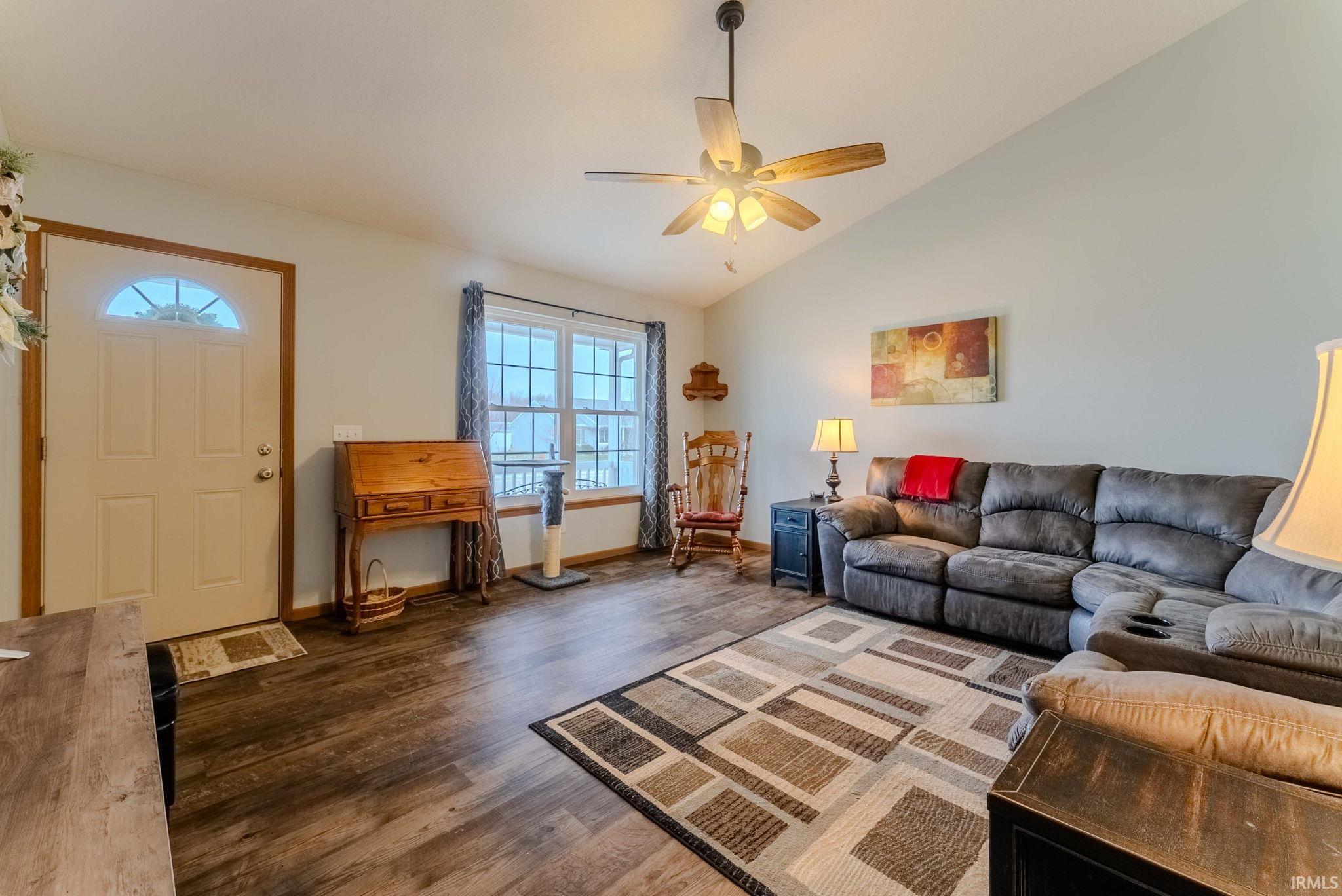 Living area with vaulted ceiling, dark wood-type flooring, and ceiling fan
