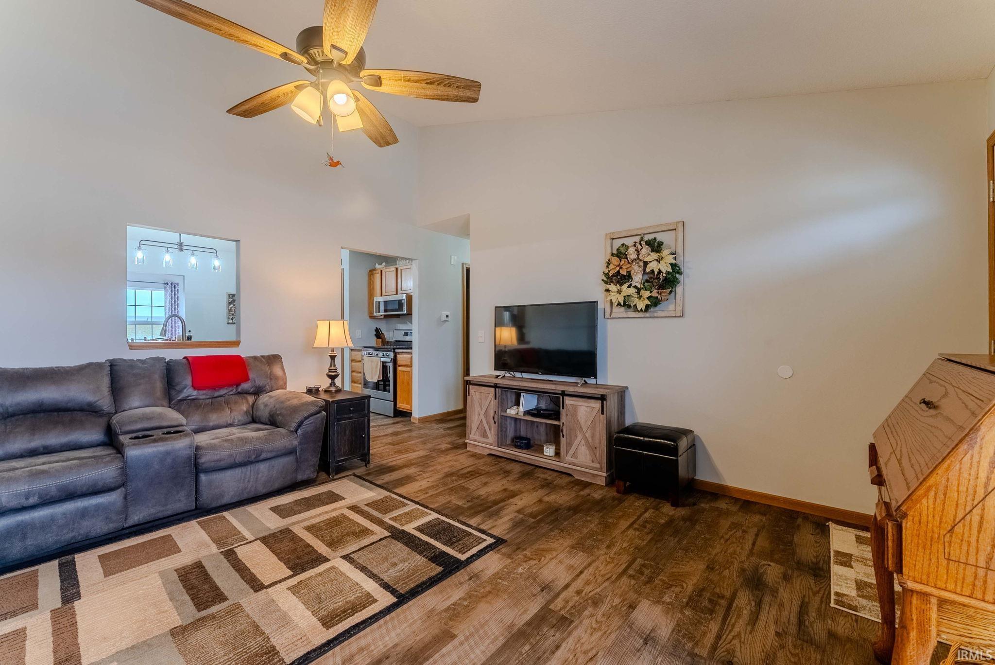 Living room featuring ceiling fan, dark wood-style flooring, and high vaulted ceiling