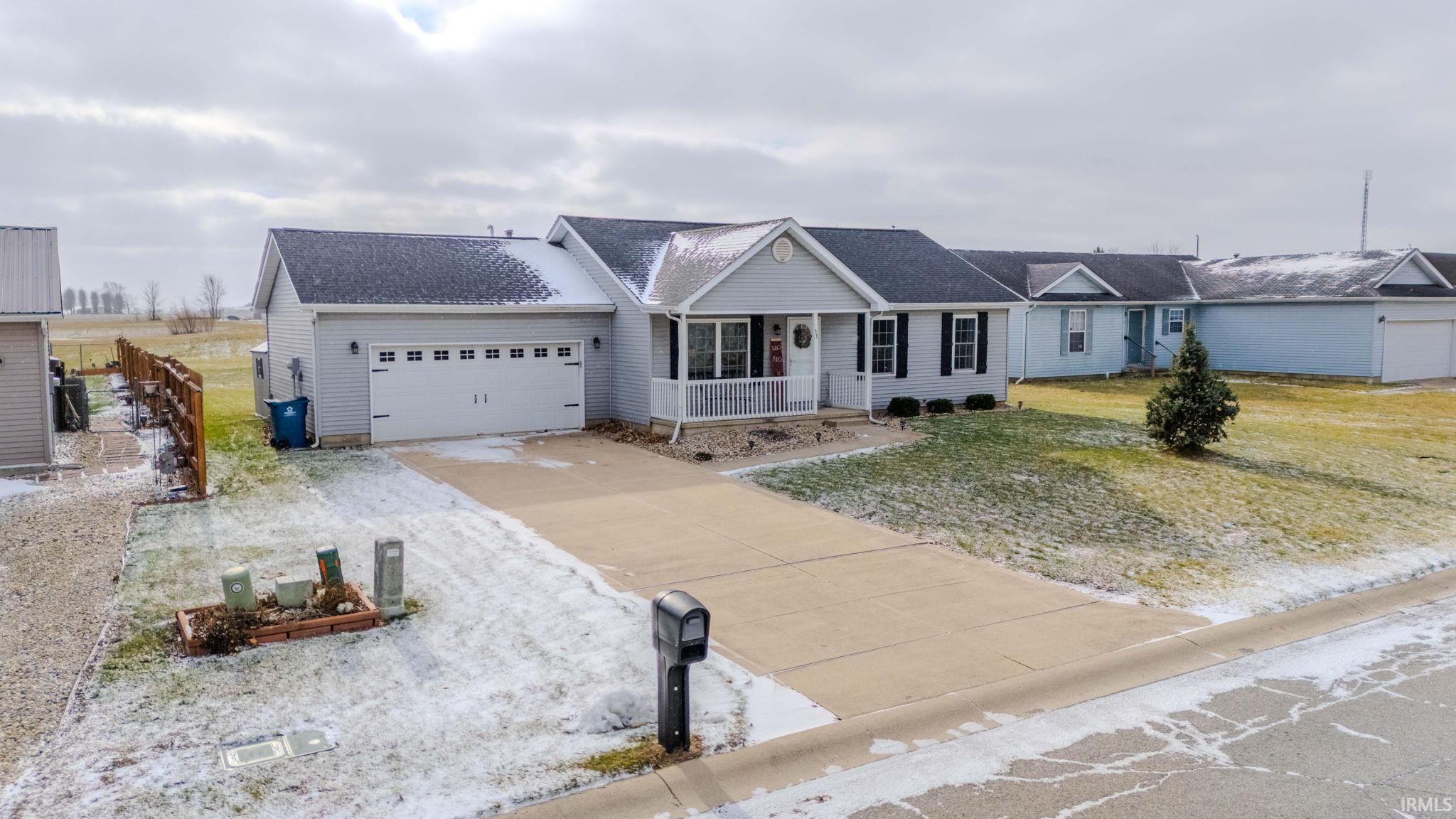 Single story home featuring a porch, driveway, a garage, and roof with shingles