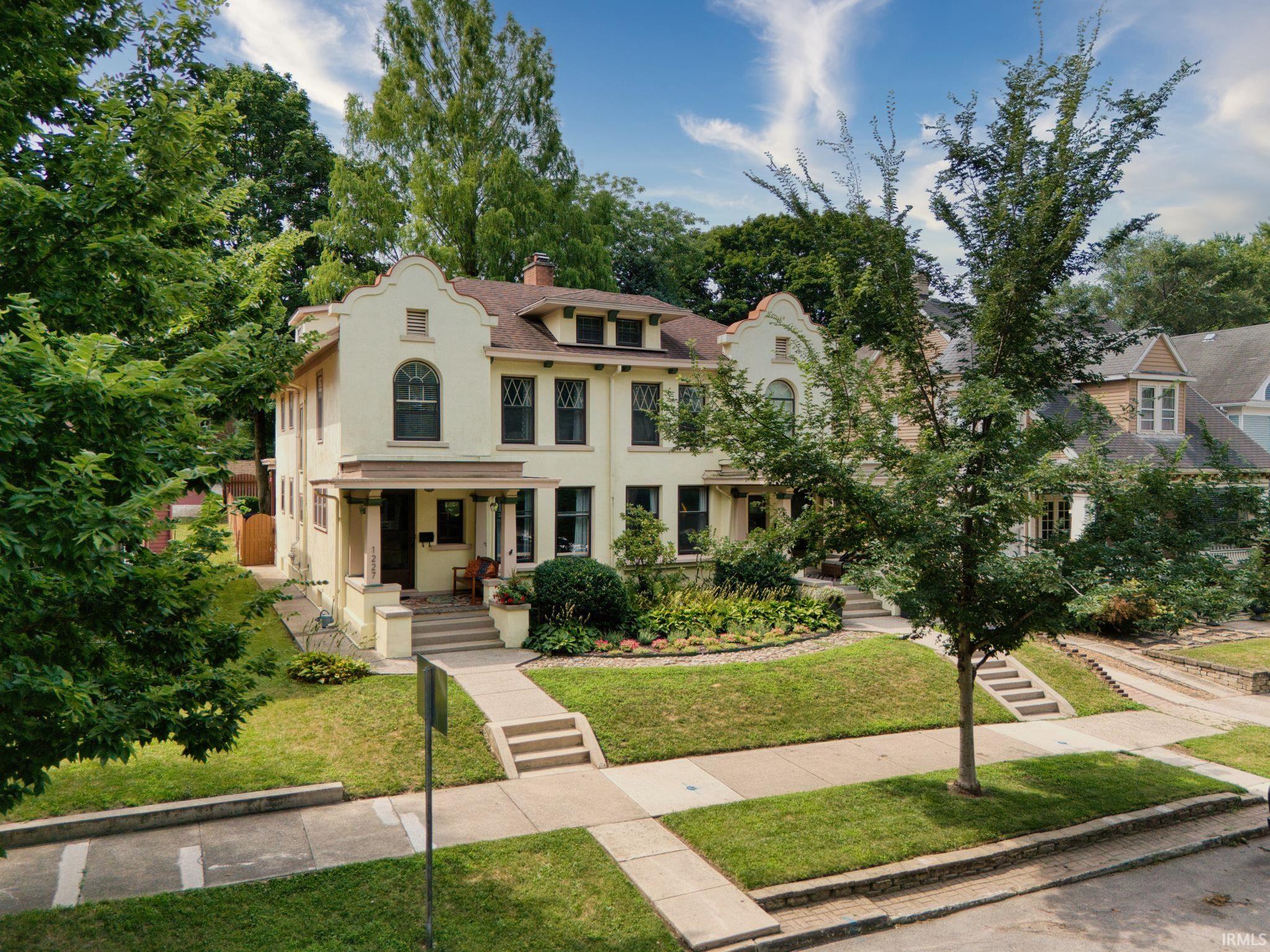 View of front of house featuring stucco siding, a chimney, a front lawn, and a porch