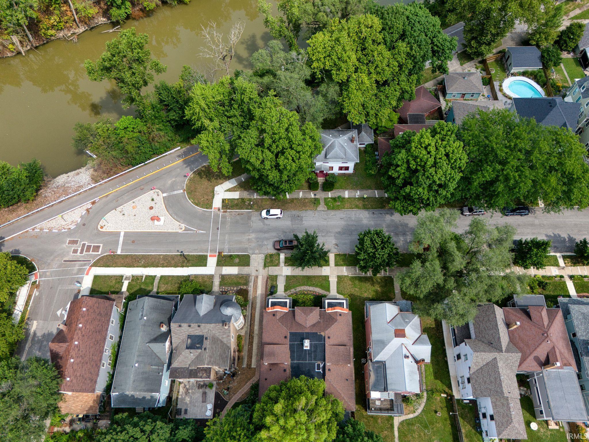 Aerial view of property and surrounding area featuring a nearby body of water and nearby suburban area