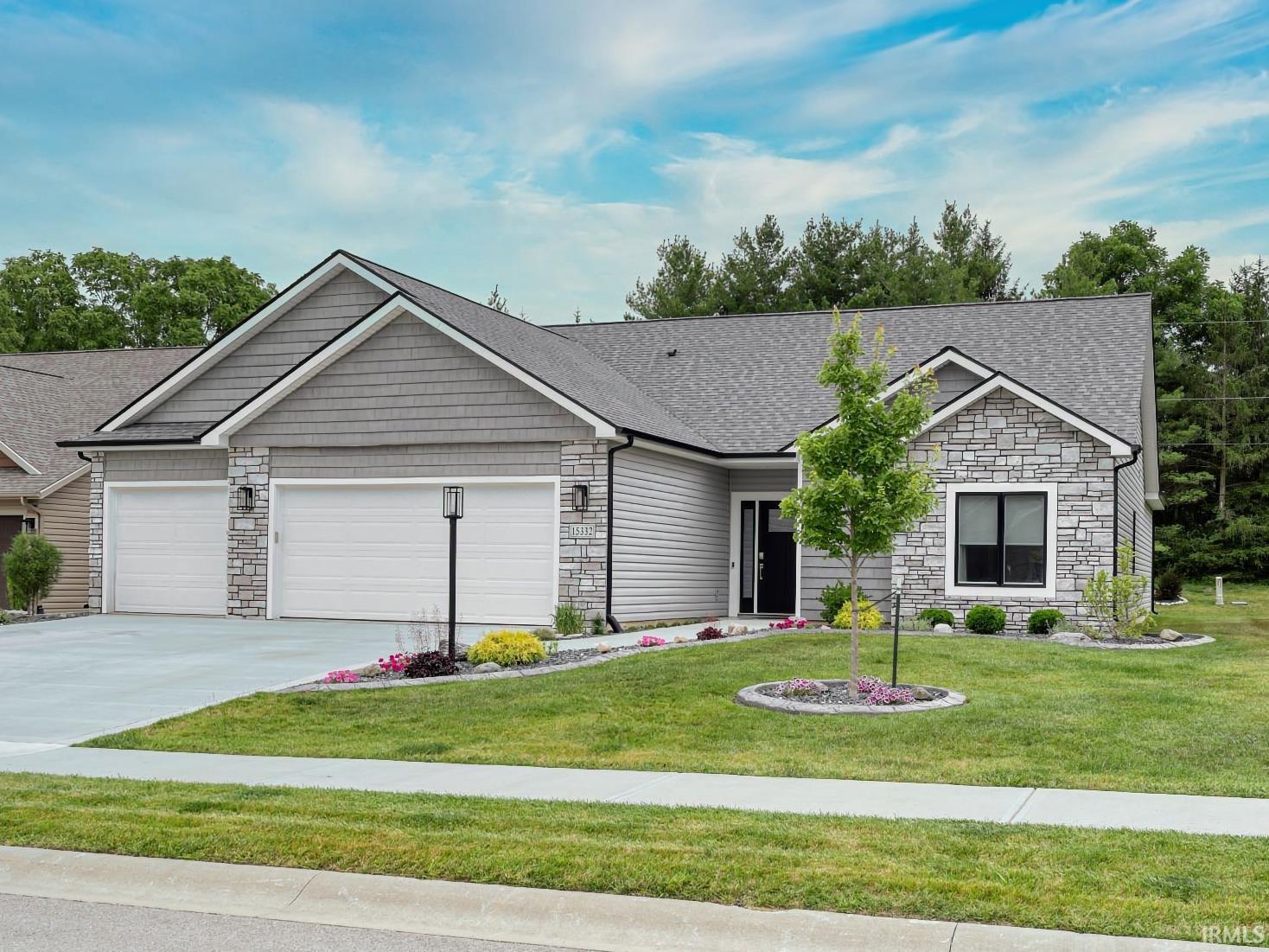 Single story home featuring stone siding, a front yard, and an attached garage