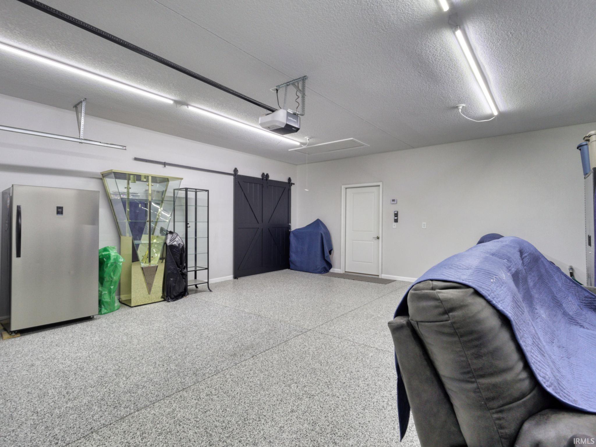 Garage with freestanding refrigerator and a garage door opener