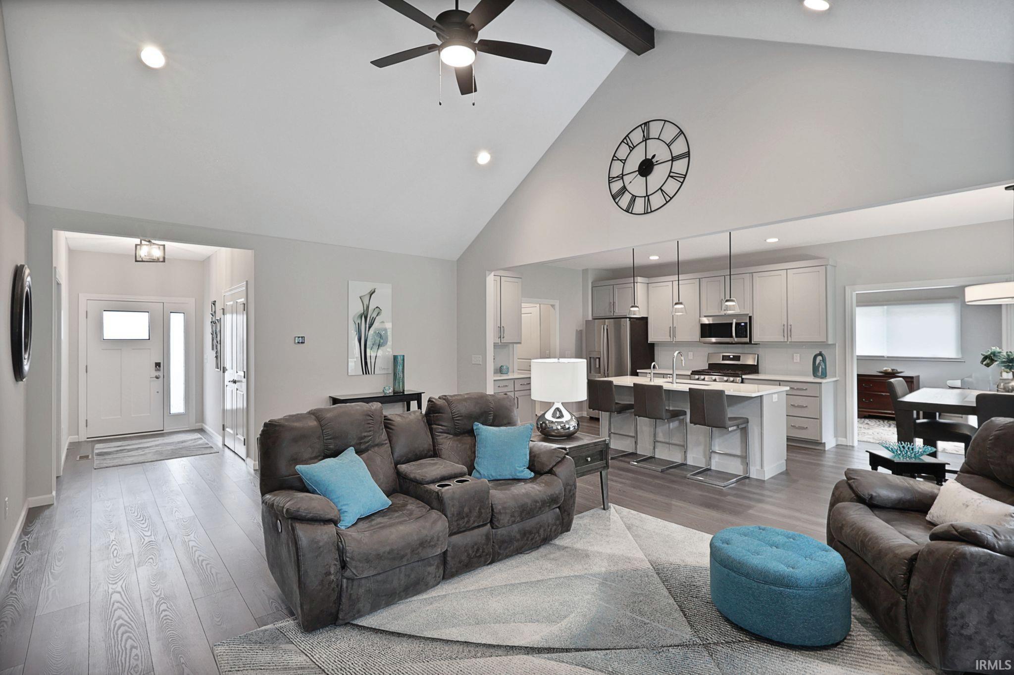 Living room with high vaulted ceiling, light wood-type flooring, recessed lighting, a ceiling fan, and beamed ceiling