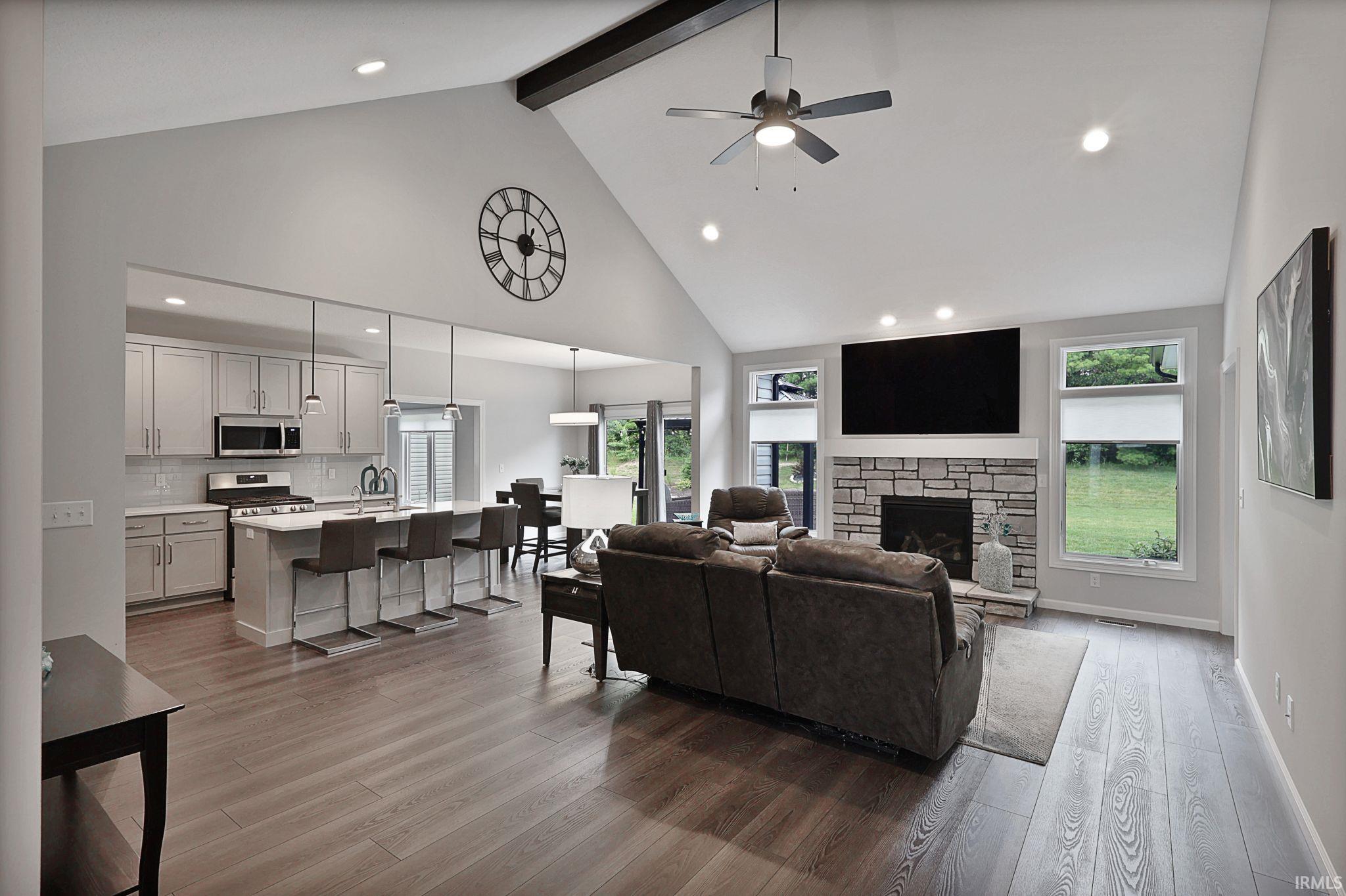 Living area featuring high vaulted ceiling, ceiling fan, a fireplace, dark wood-style flooring, and recessed lighting