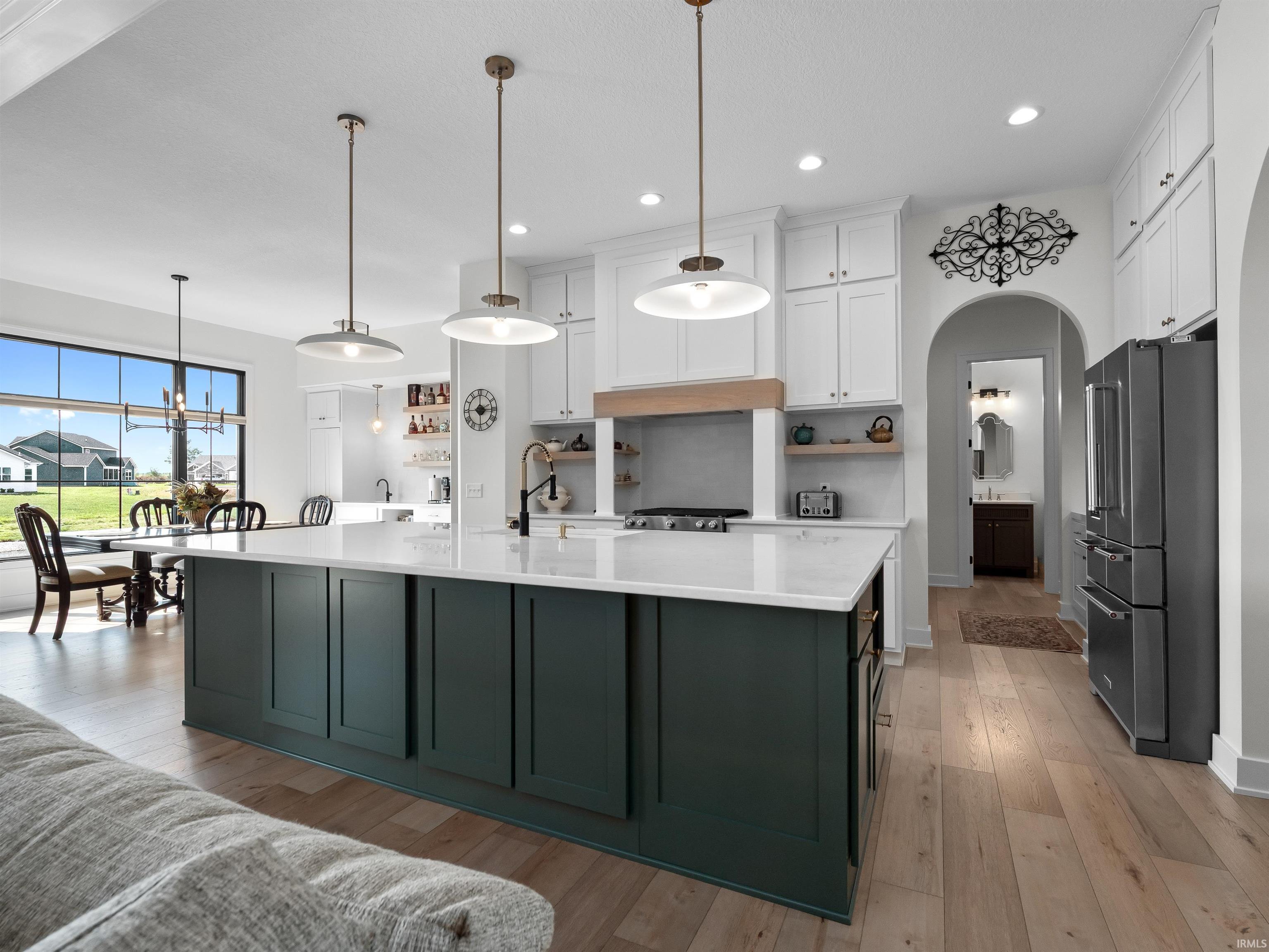 Kitchen with white cabinetry, high end fridge, pendant lighting, a spacious island, and open shelves