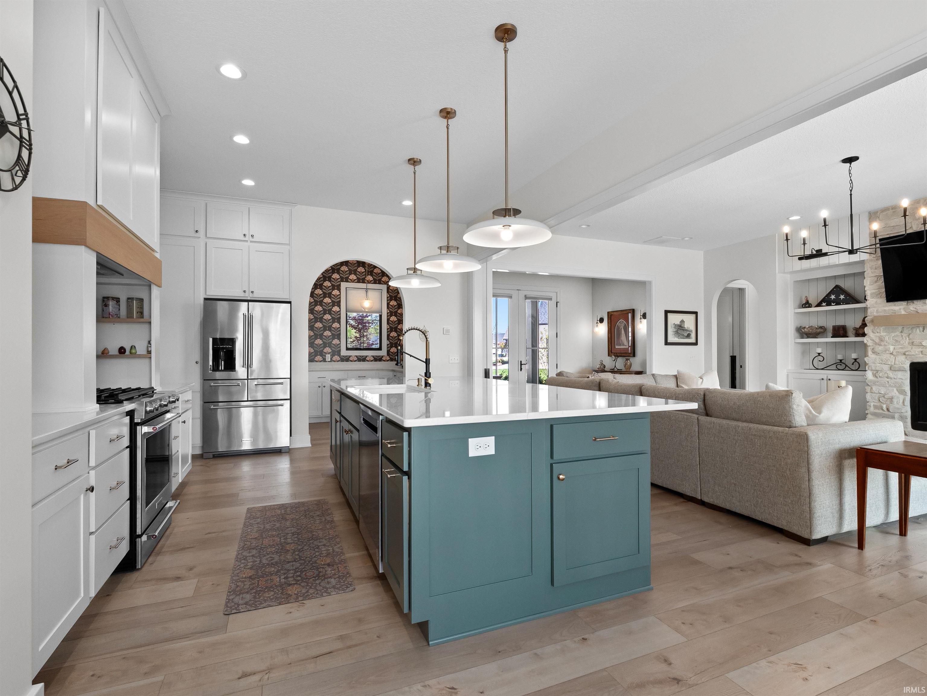 Kitchen featuring built in features, white cabinets, open floor plan, stainless steel appliances, and a kitchen island with sink