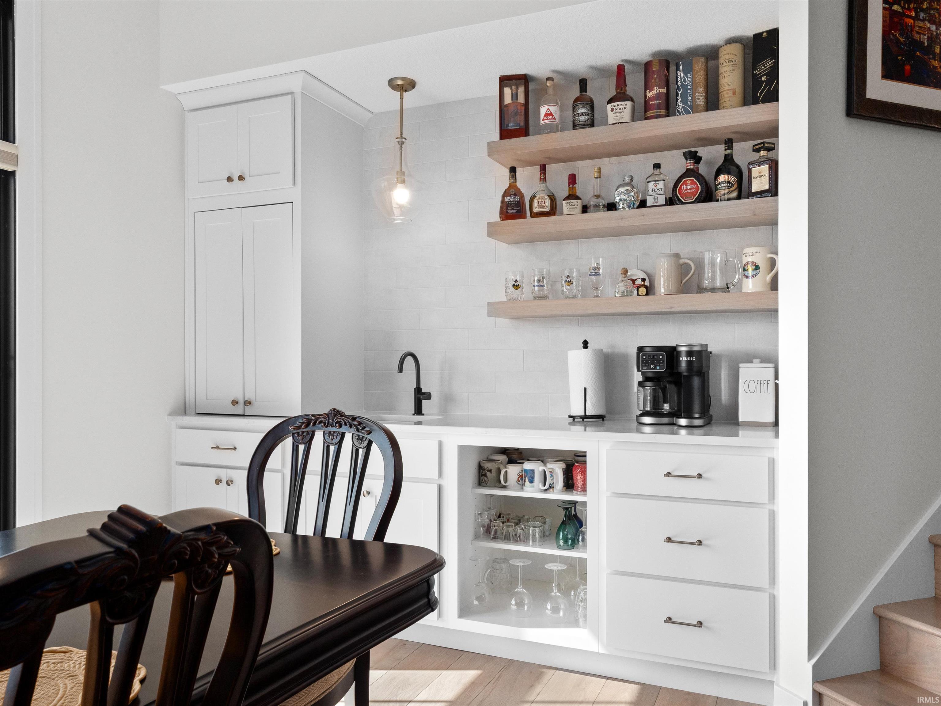 Indoor wet bar with open shelves, white cabinetry, pendant lighting, and decorative backsplash