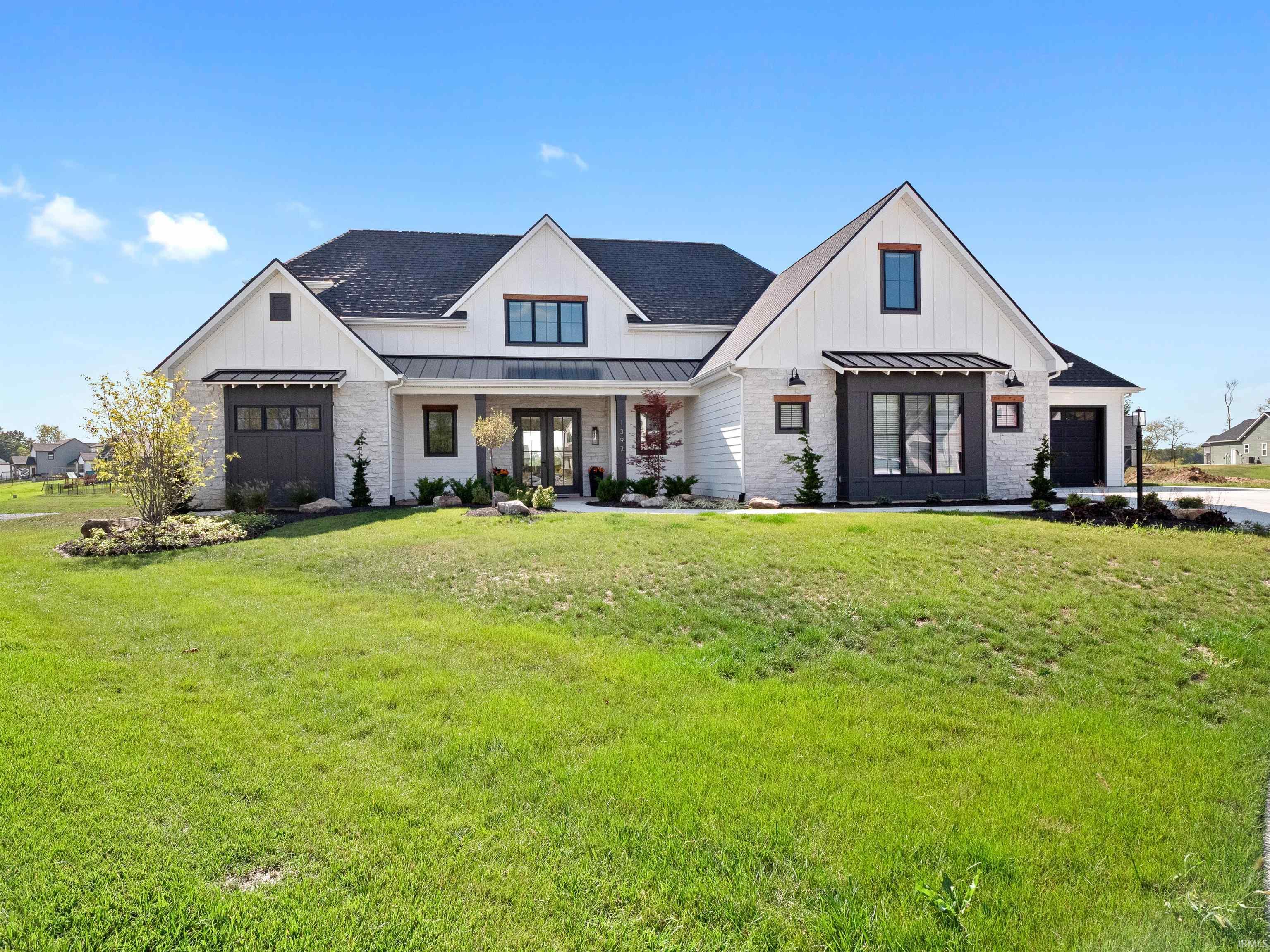Modern farmhouse with covered porch, a standing seam roof, a metal roof, a front yard, and board and batten siding