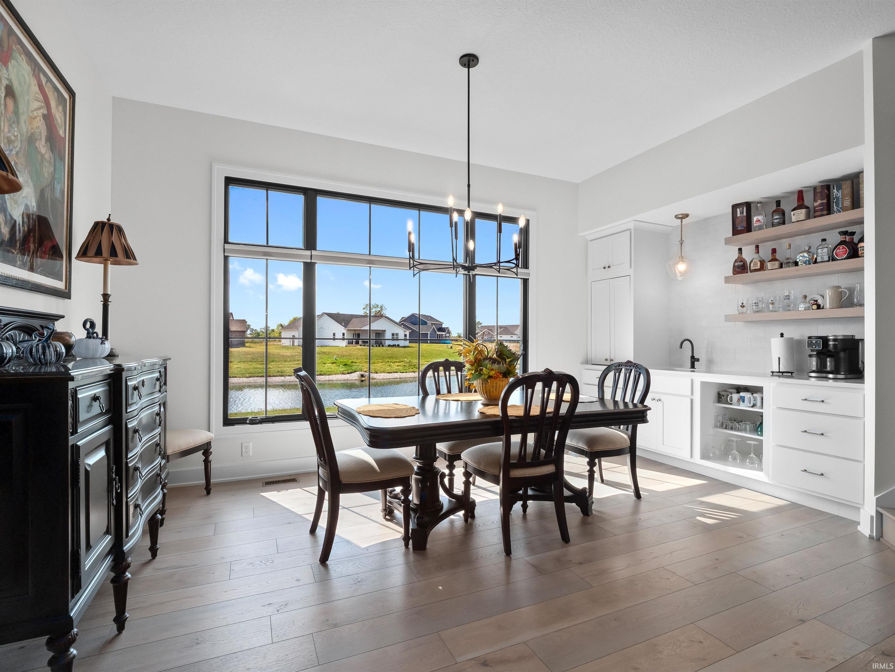Dining area with a water view, a chandelier, and light wood-style floors