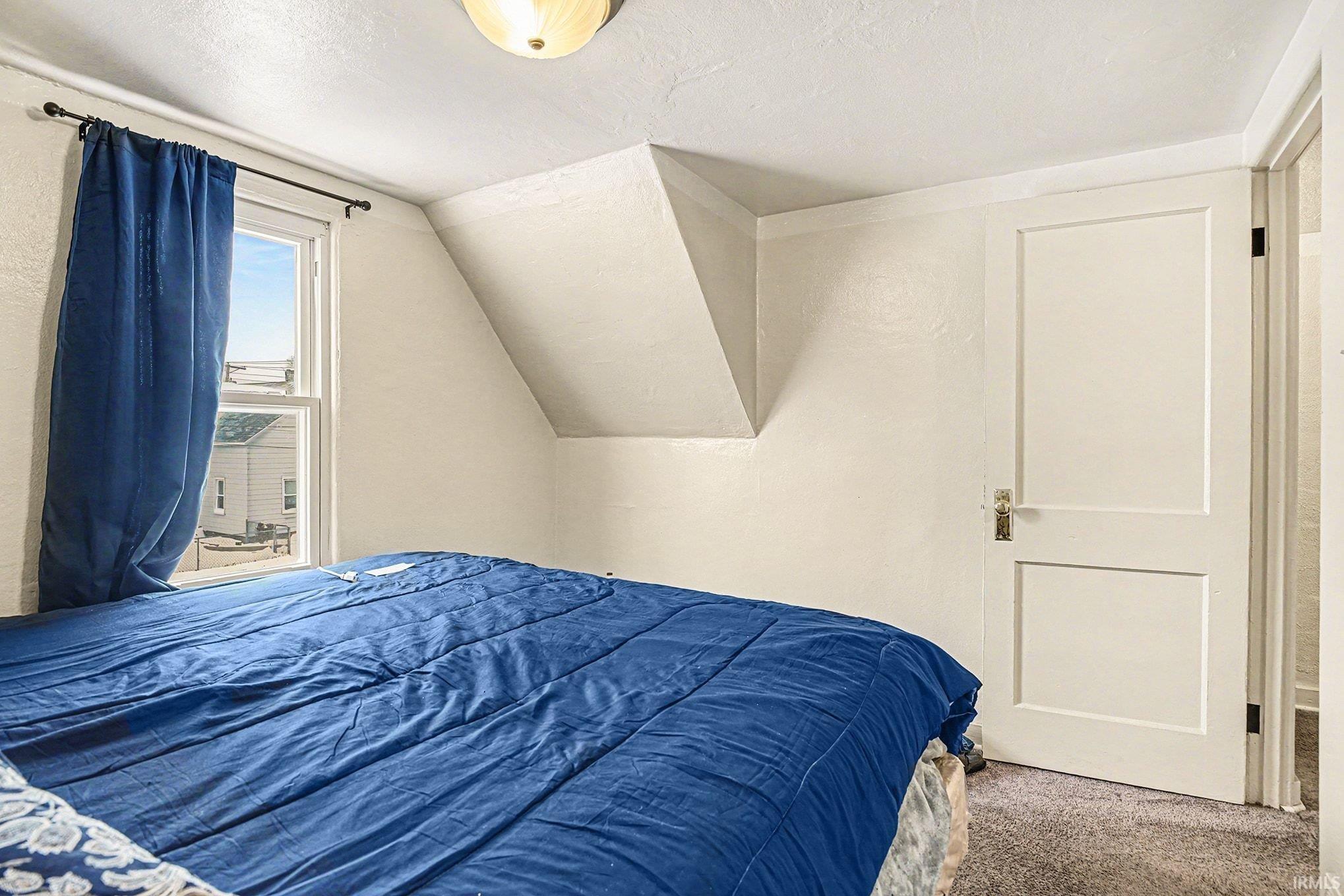 Carpeted bedroom with lofted ceiling and a textured ceiling