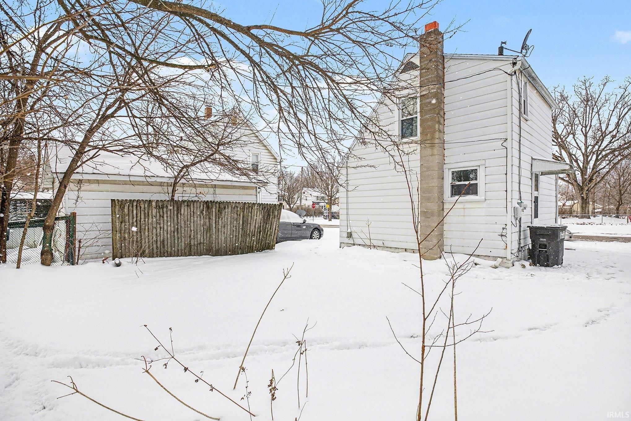 Snow covered property featuring a chimney