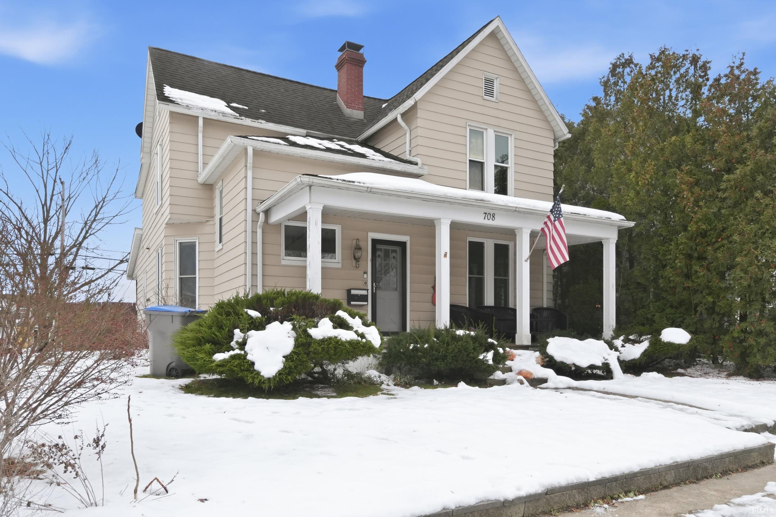 View of front of property featuring a porch, a shingled roof, and a chimney