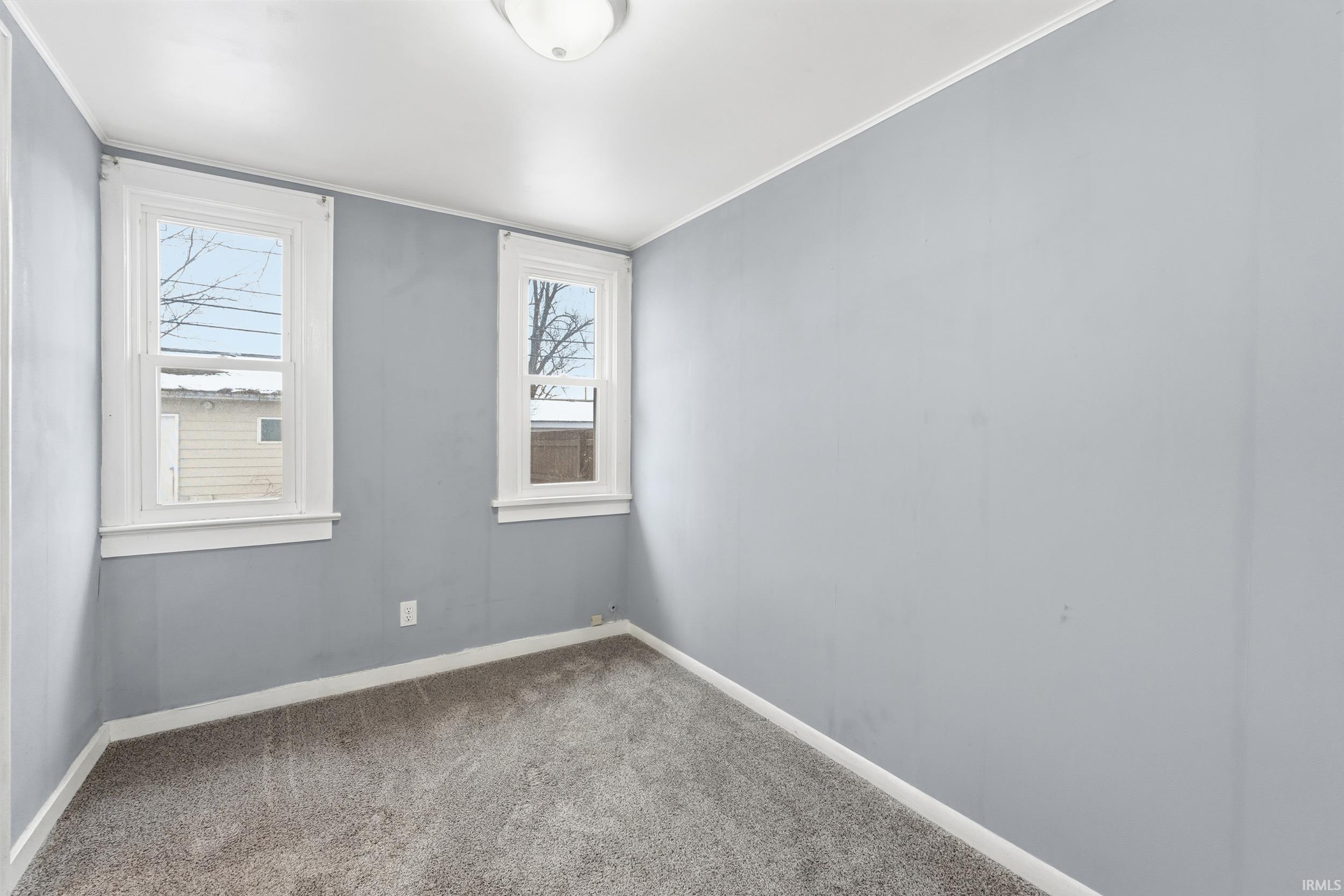 Carpeted empty room with baseboards and crown molding