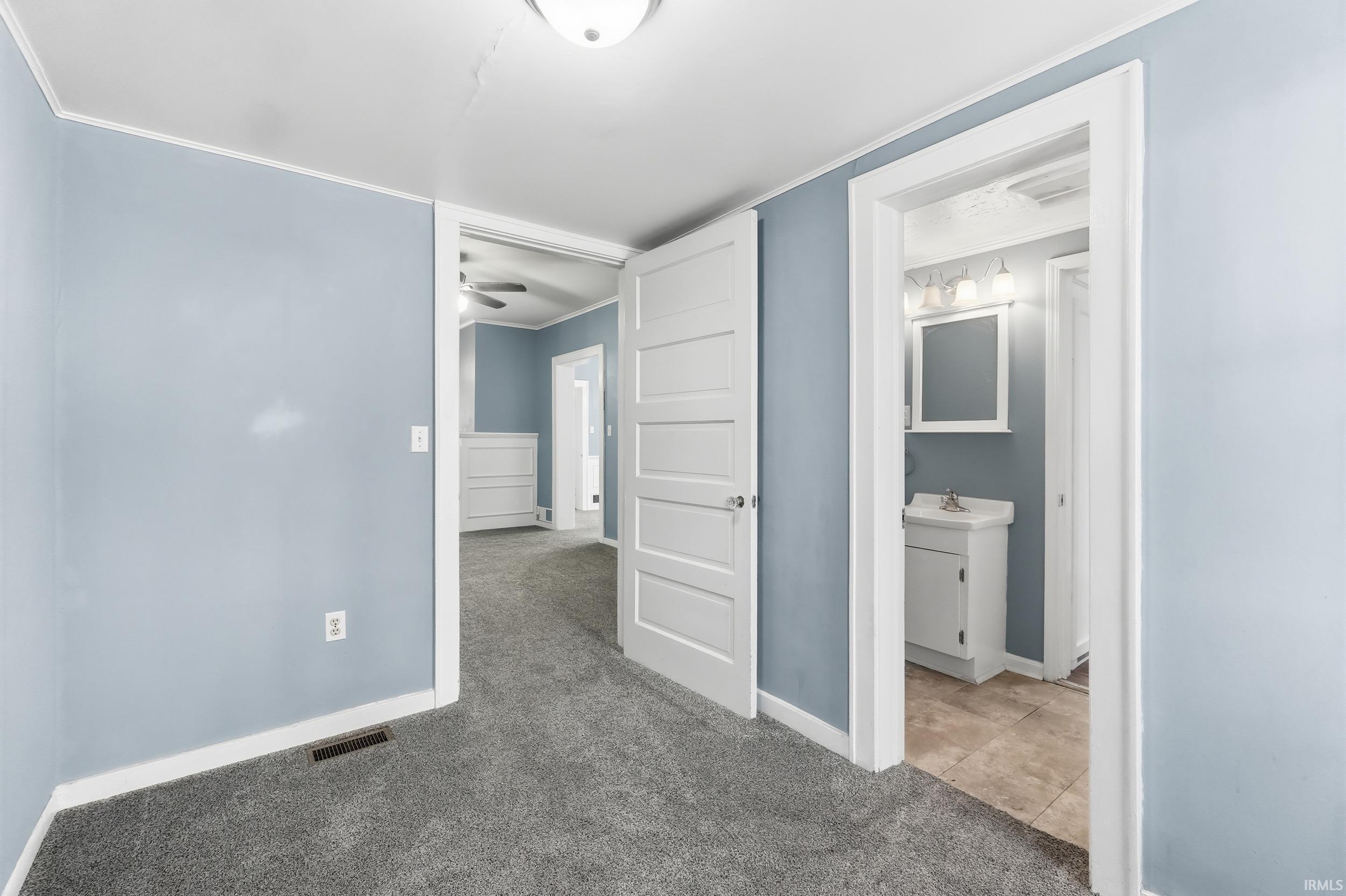 Unfurnished bedroom with carpet floors, ensuite bath, and crown molding