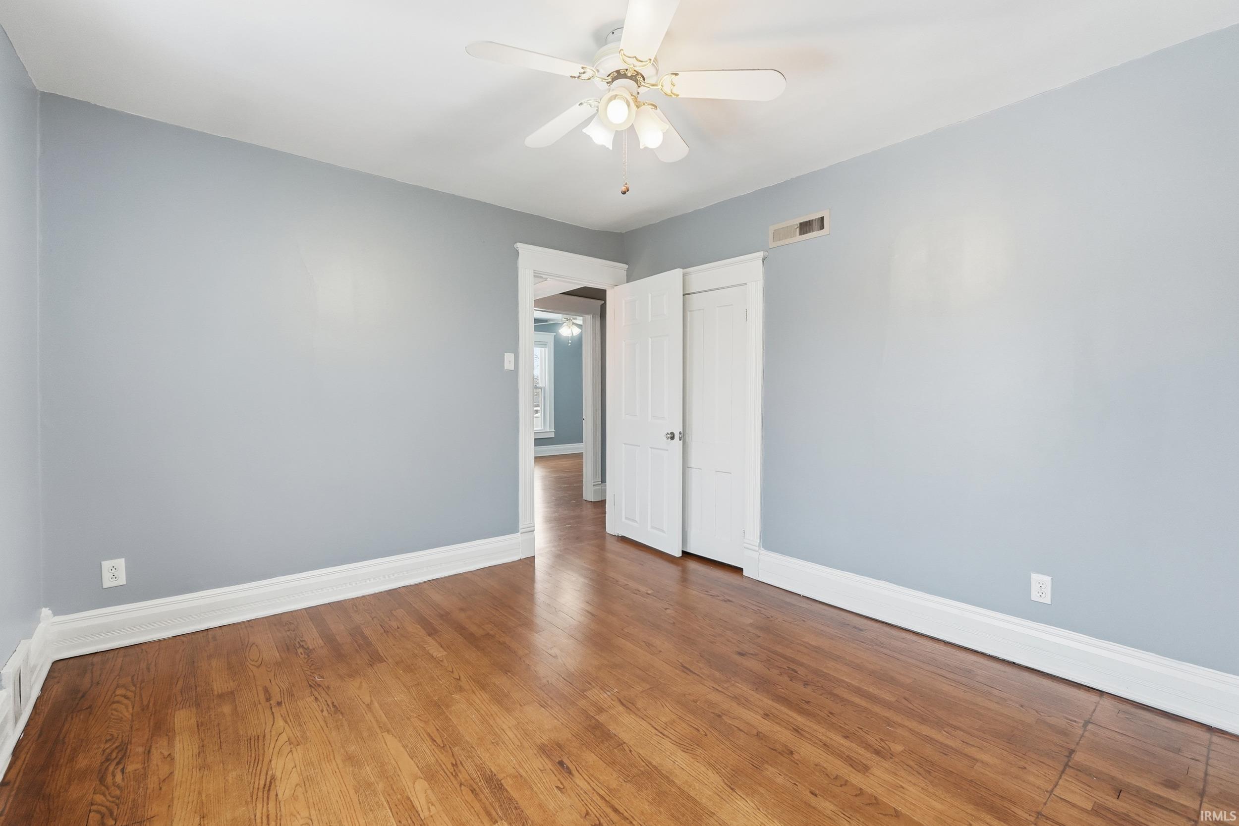 Unfurnished bedroom with ceiling fan, hardwood / wood-style flooring, and a closet