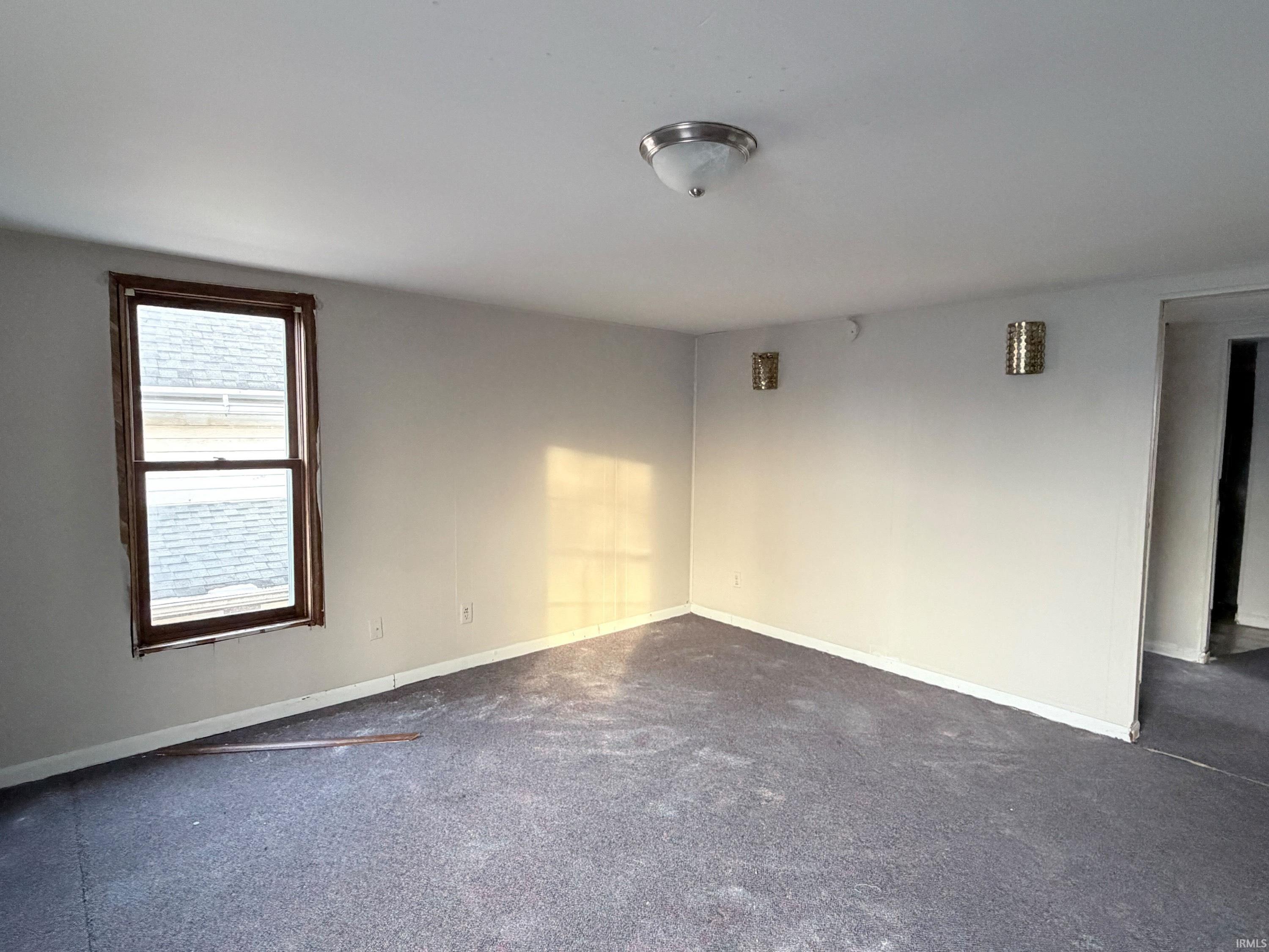 Spare room with baseboards and dark colored carpet