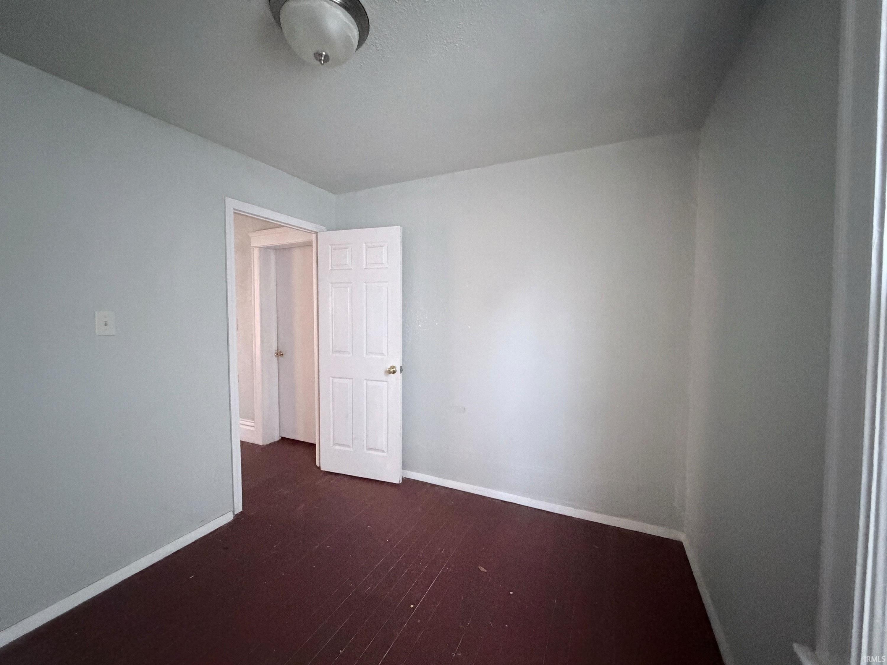 Unfurnished room featuring baseboards and dark wood-style flooring