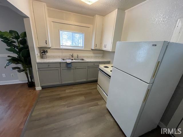 Kitchen featuring white appliances, gray cabinets, light countertops, a textured ceiling, and dark wood finished floors
