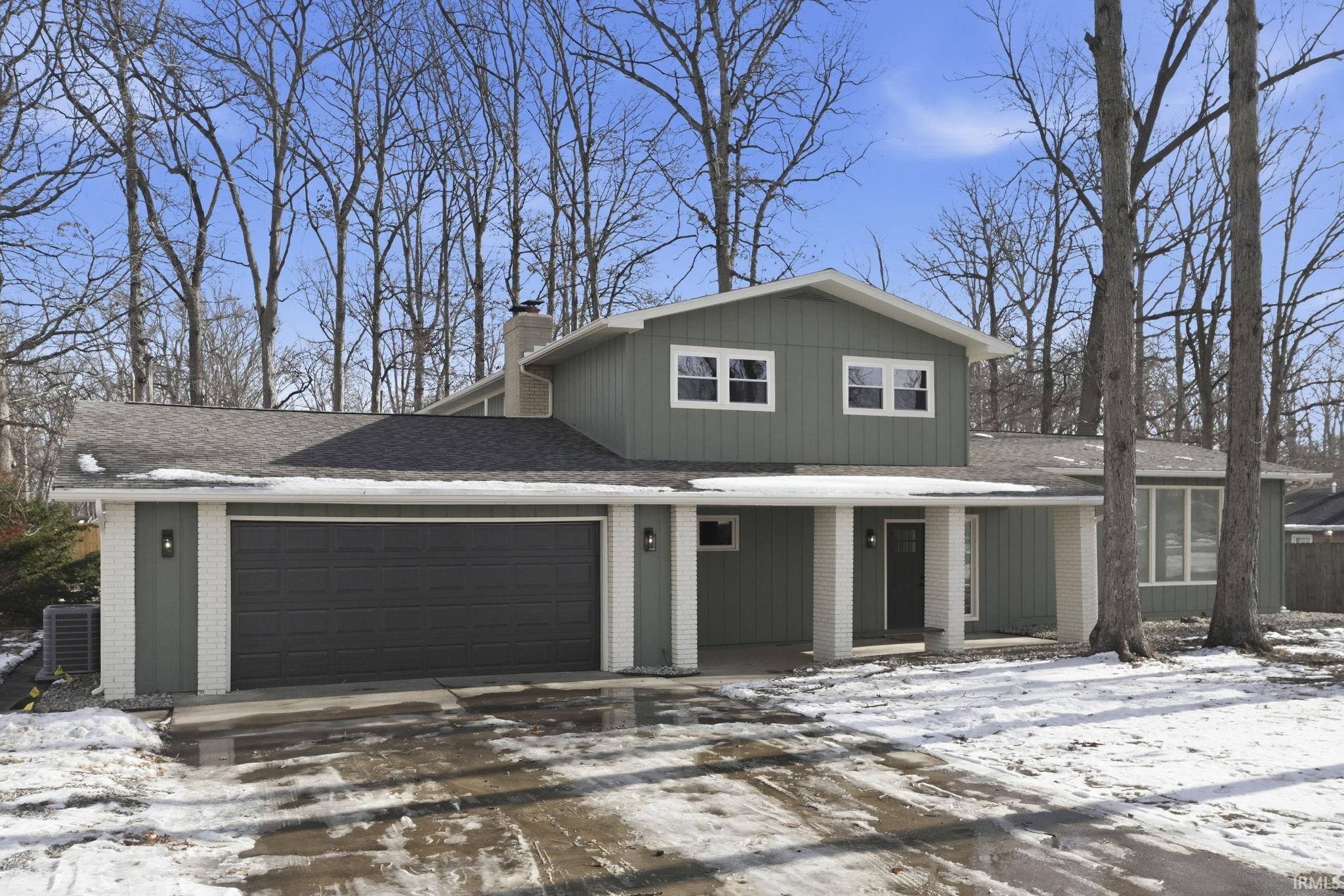 View of front of home featuring brick siding, an attached garage, roof with shingles, driveway, and a porch