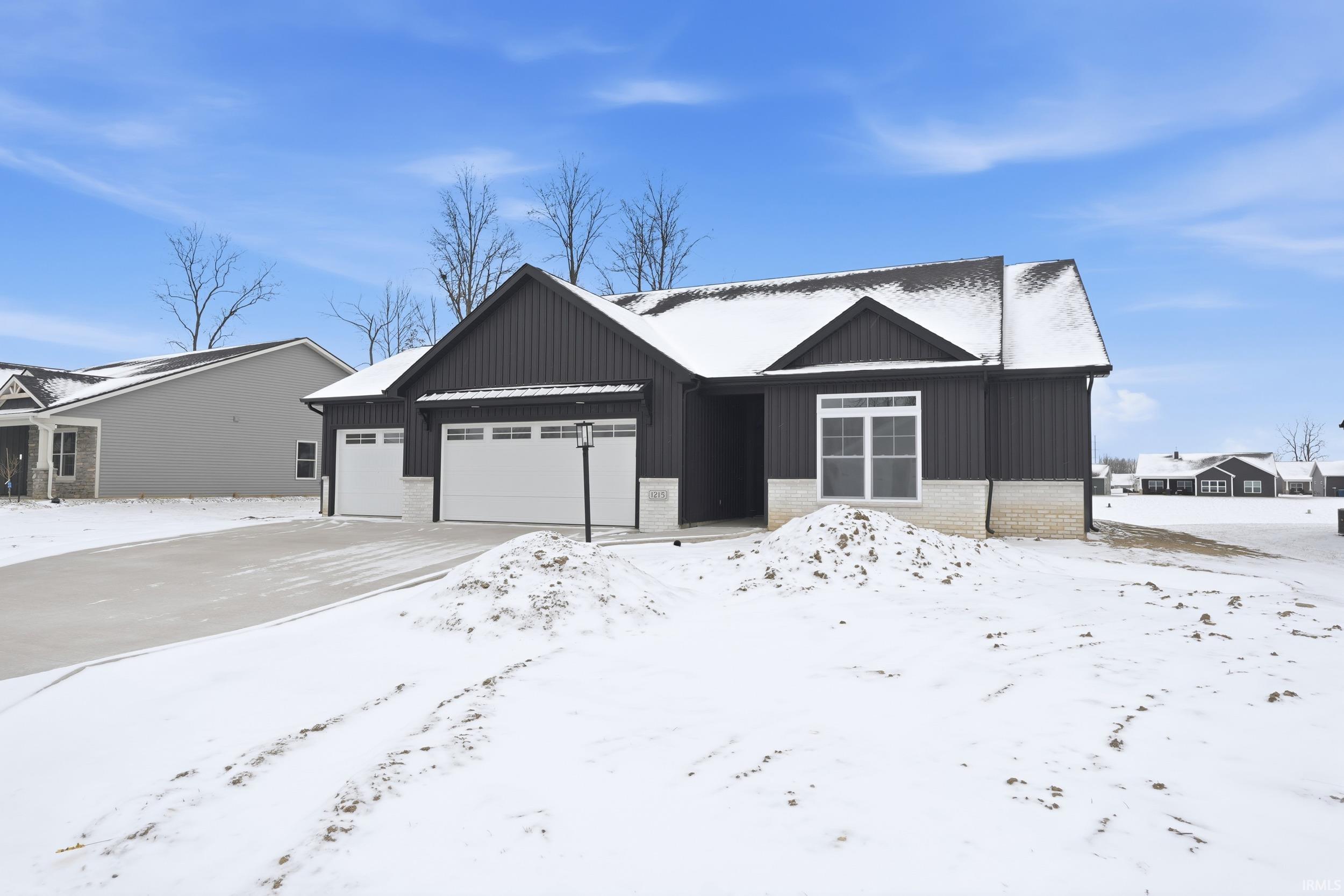 View of front of house with a garage, board and batten siding, brick siding, and driveway