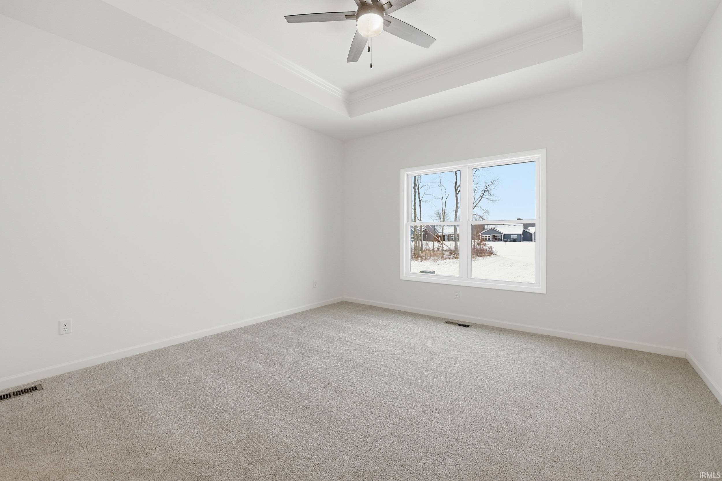Unfurnished room with carpet floors, a tray ceiling, crown molding, and ceiling fan