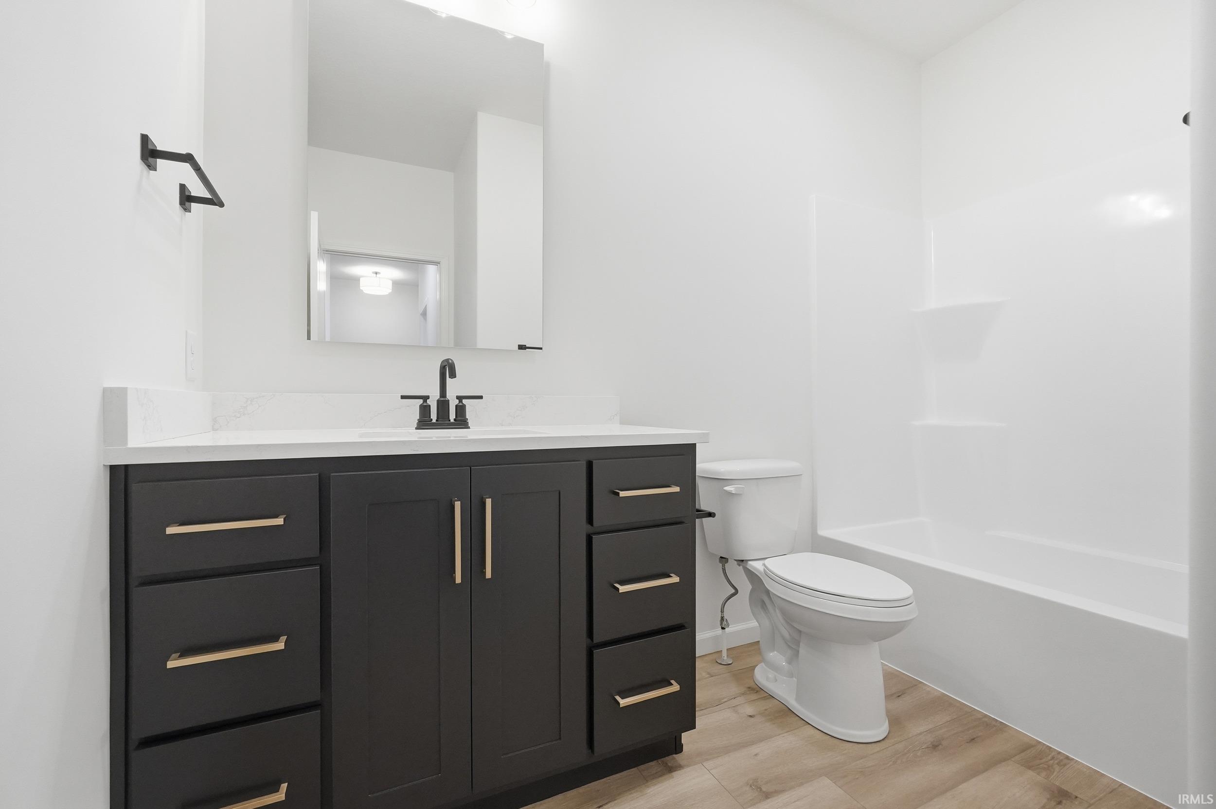 Bathroom with vanity, light wood finished floors, and  shower combination