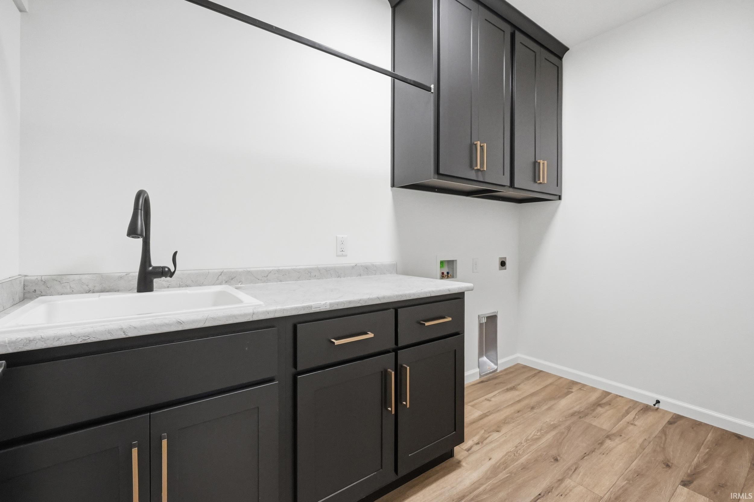 Washroom featuring cabinet space, light wood-style floors, washer hookup, and hookup for an electric dryer