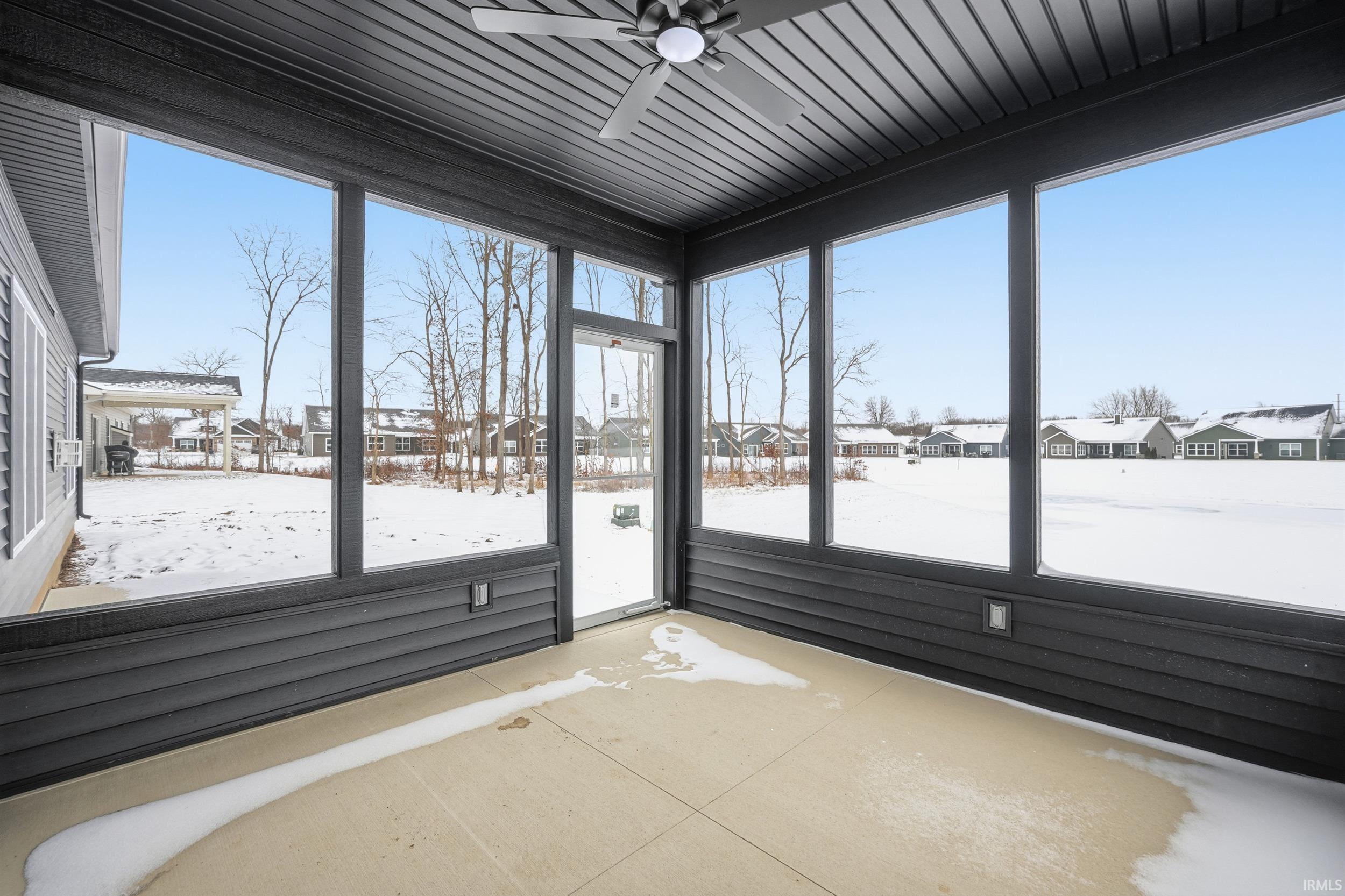 Unfurnished sunroom with a ceiling fan, a residential view, and plenty of natural light