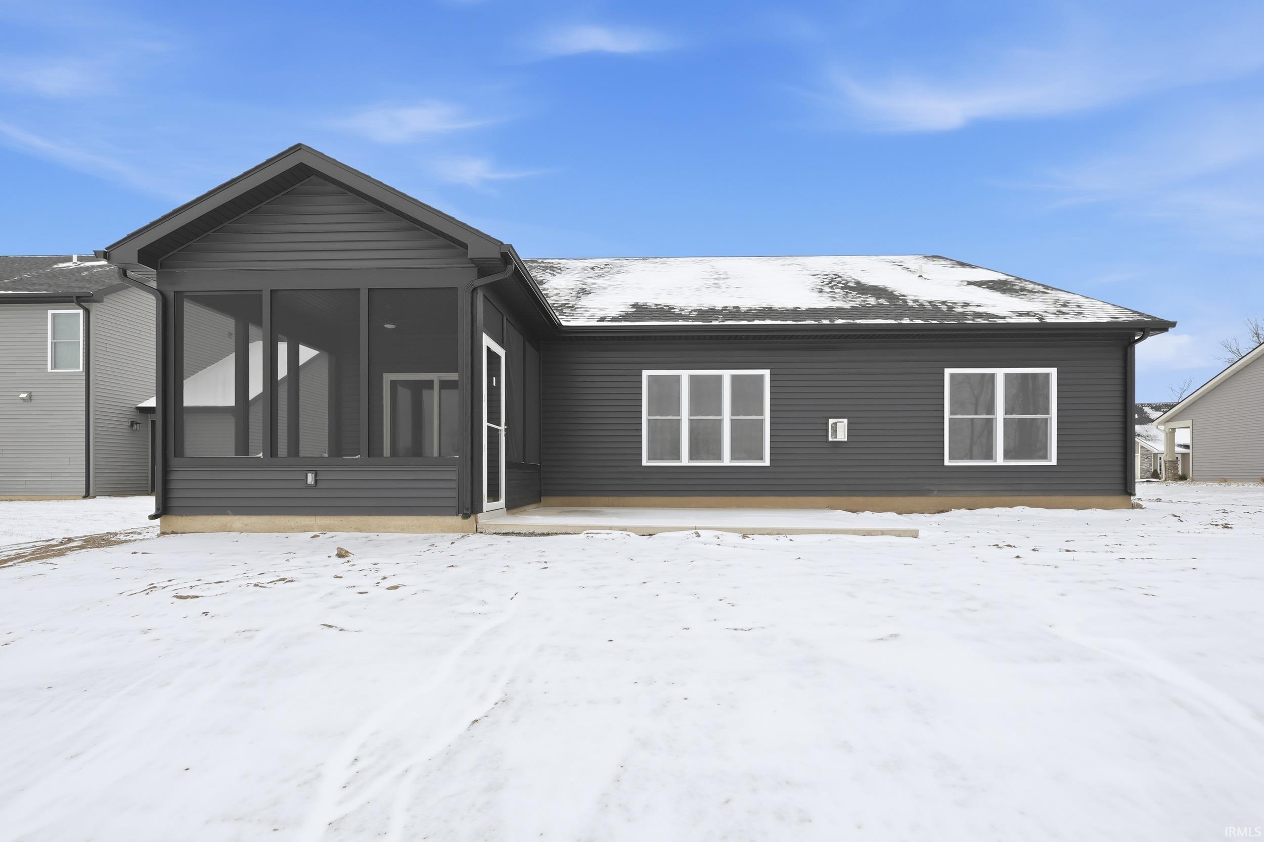 Snow covered house featuring a sunroom and a patio