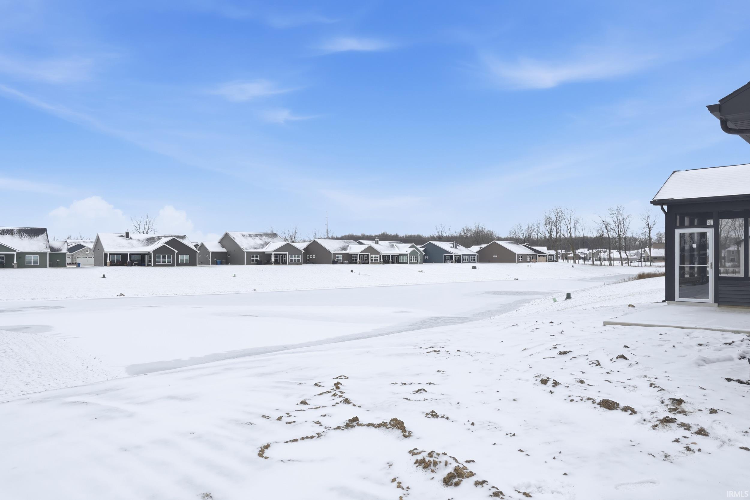 Yard covered in snow with a residential view and a sunroom
