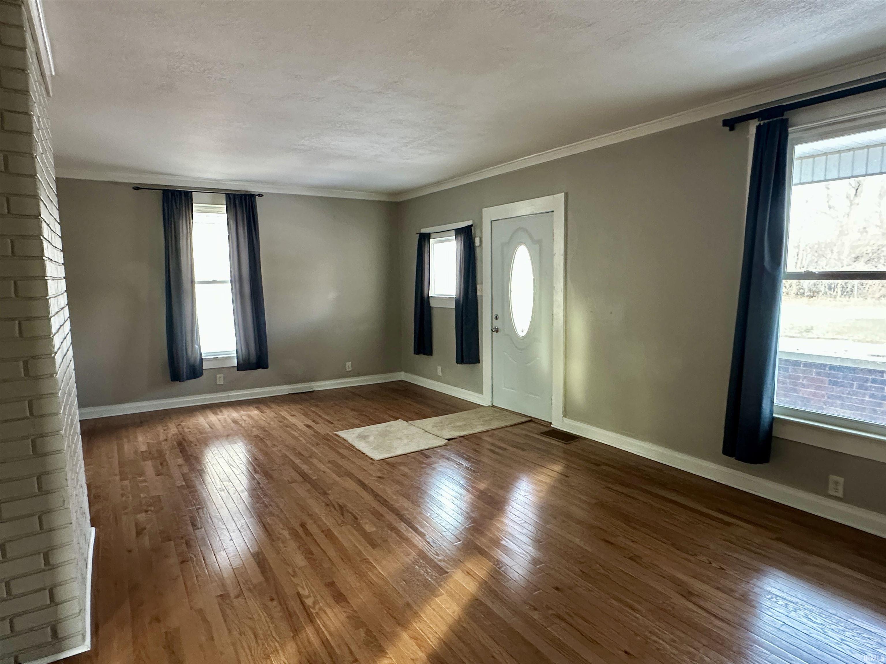 Foyer featuring hardwood / wood-style floors, crown molding, and a textured ceiling