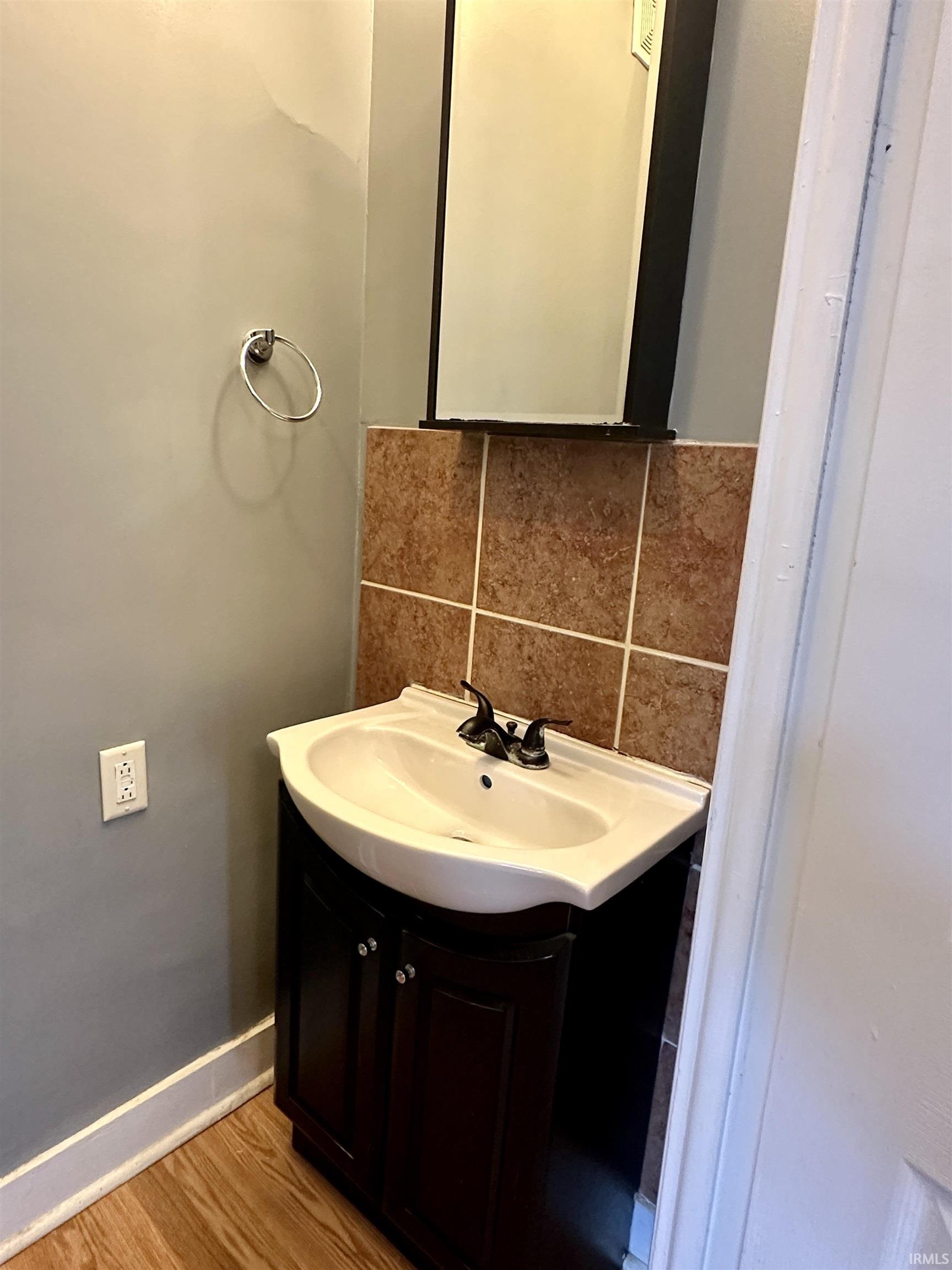 Bathroom featuring vanity, decorative backsplash, and light wood-style floors