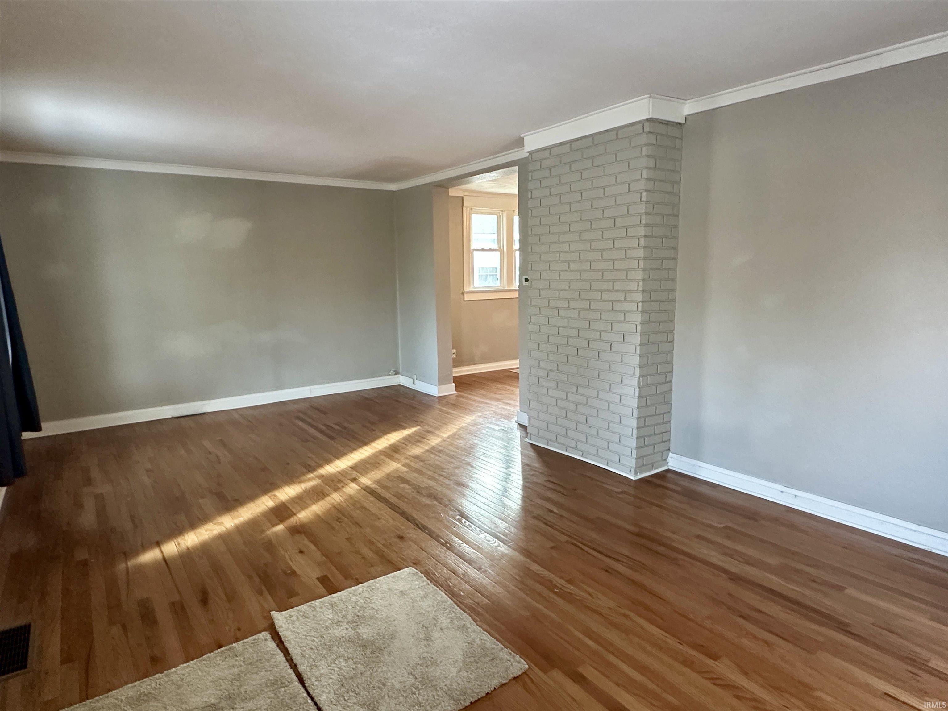Empty room with dark wood-type flooring and crown molding