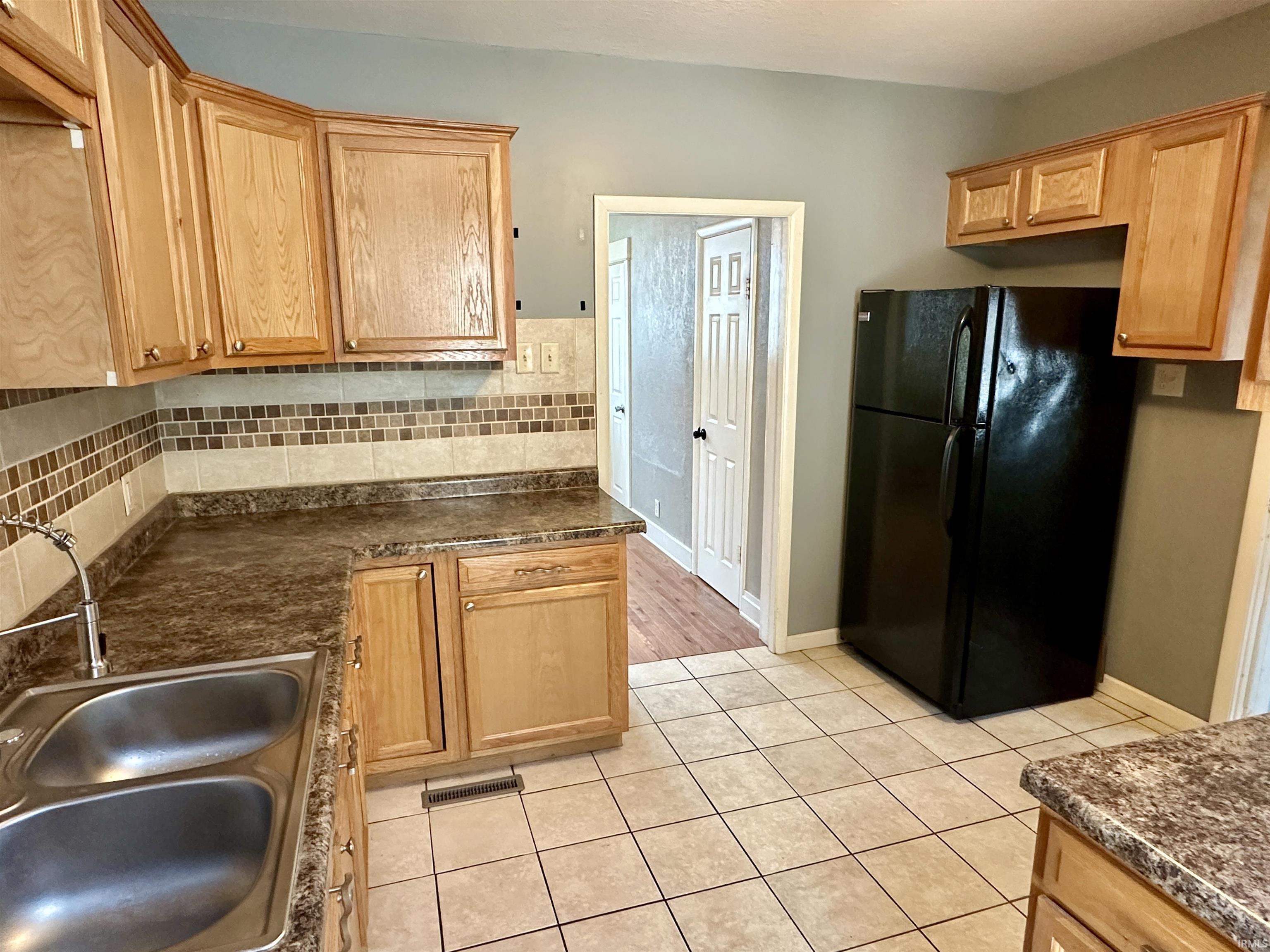 Kitchen featuring freestanding refrigerator, backsplash, and light tile patterned floors