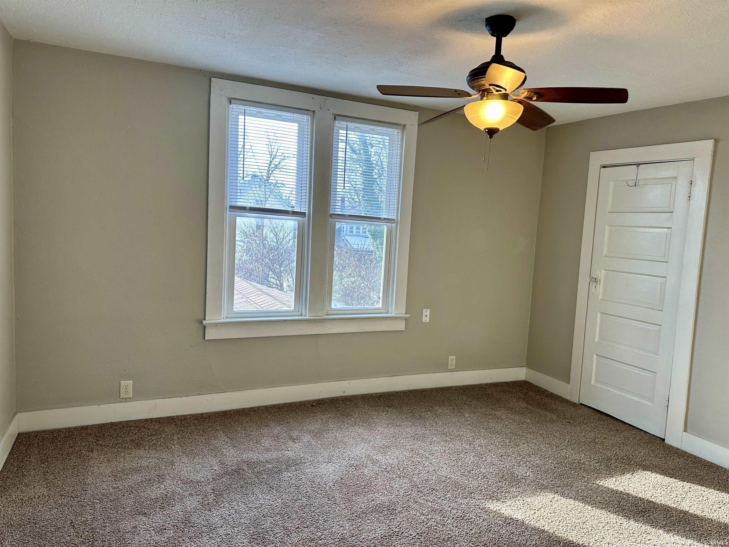 Carpeted empty room featuring a textured ceiling and ceiling fan