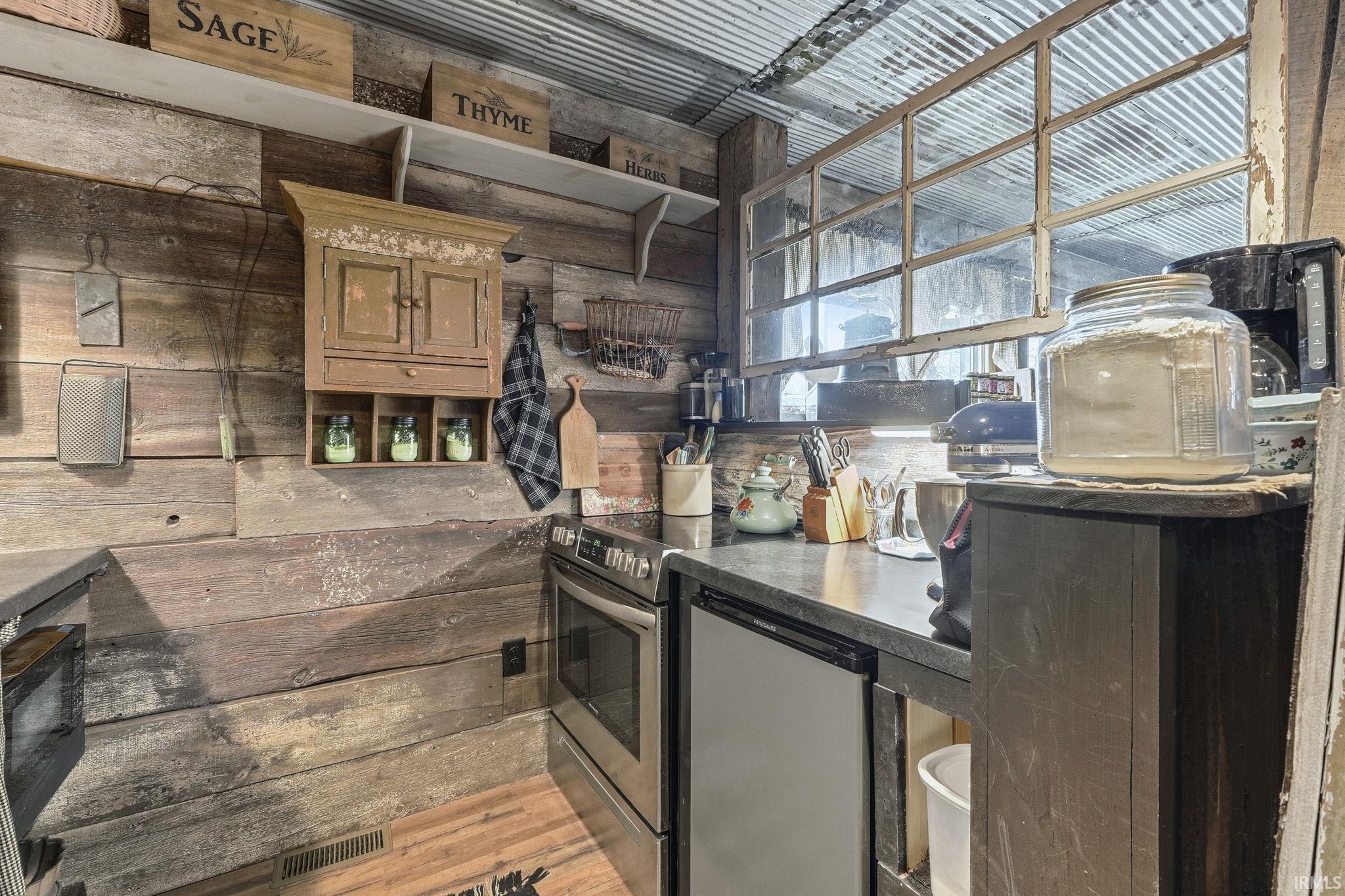 Kitchen featuring wood walls, dark countertops, and stainless steel appliances