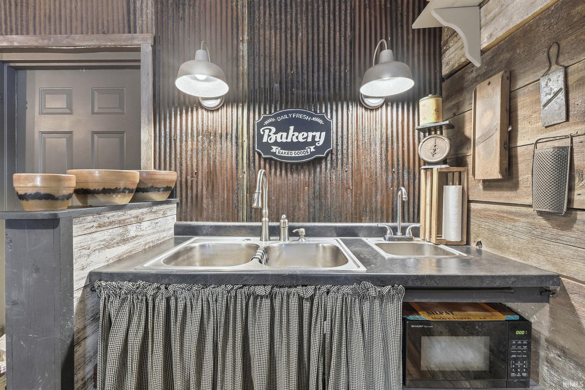 Kitchen featuring dark countertops, black microwave, and wood walls
