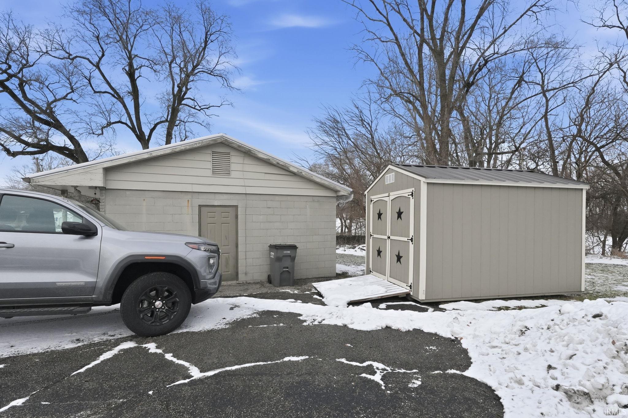 View of snowy exterior featuring a storage shed