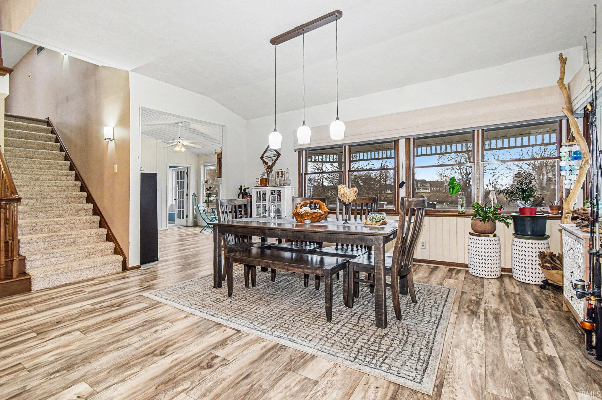 Dining space featuring light wood finished floors, stairway, lofted ceiling, and french doors