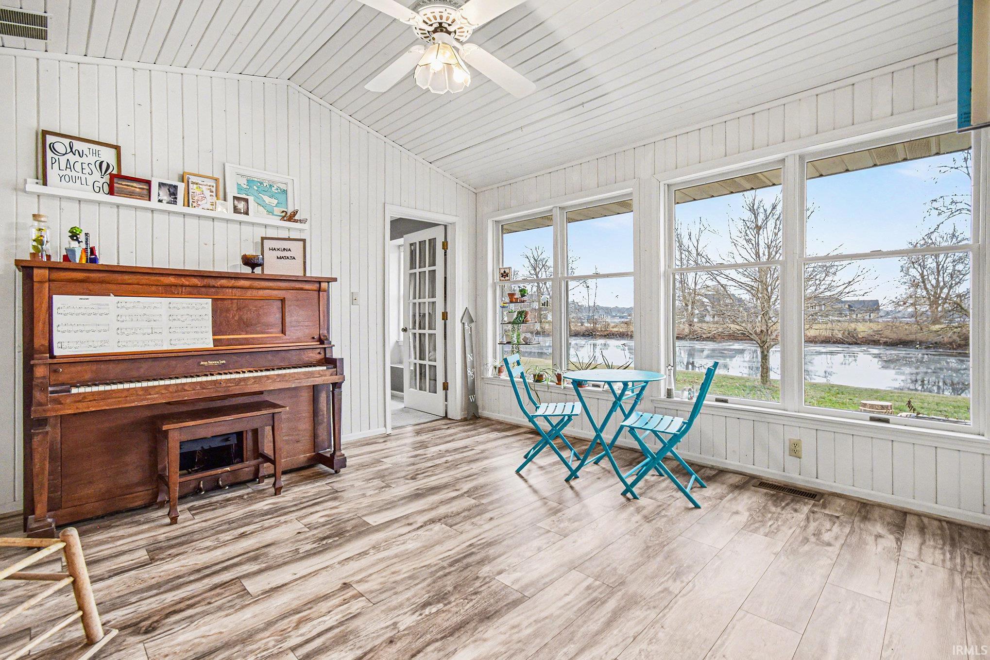 Sunroom / solarium with vaulted ceiling, wood finished floors, wood walls, a water view, and wood ceiling