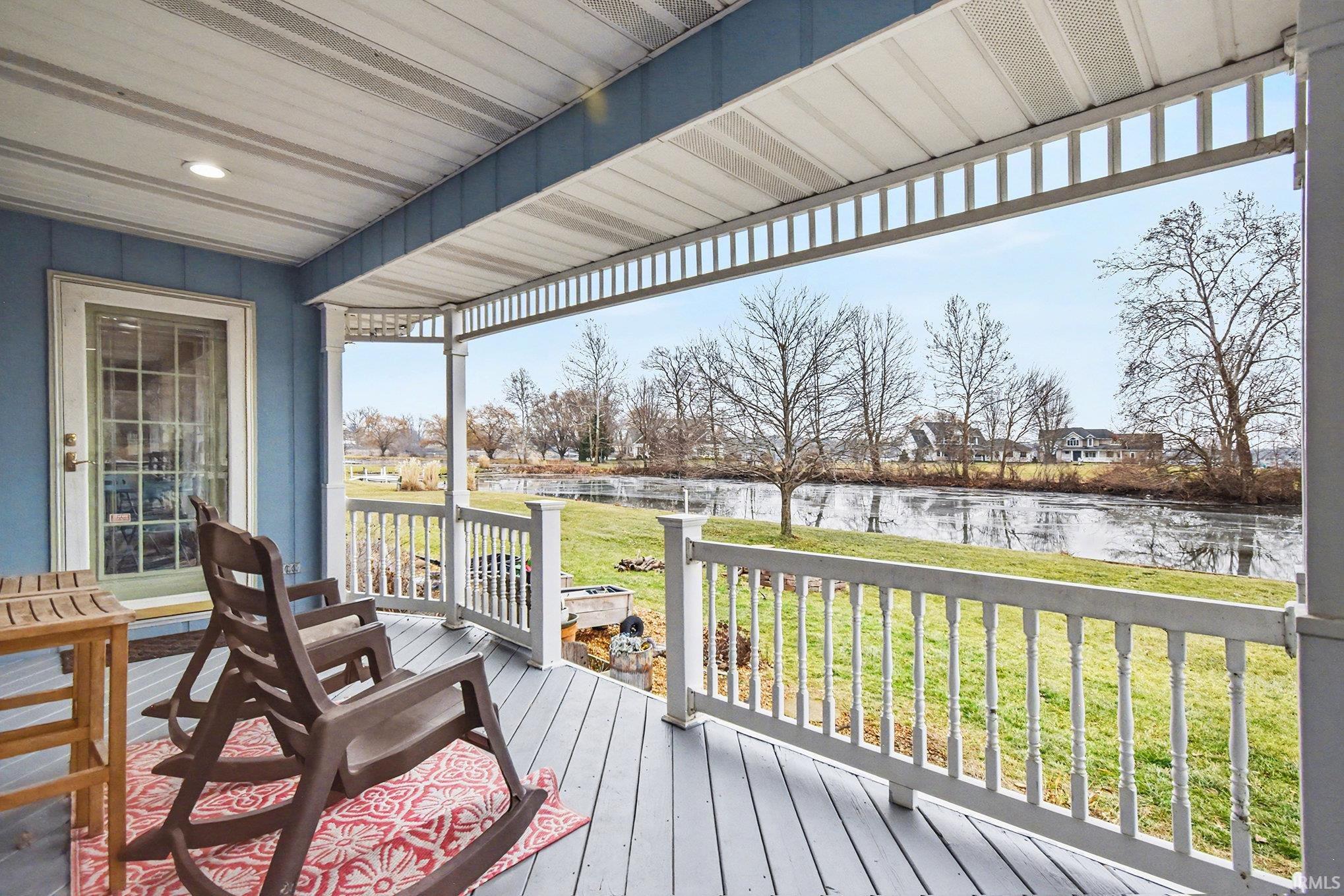 Wooden terrace with a water view and a yard